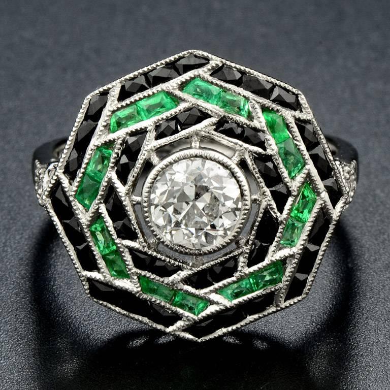 A Stunning Platinum Ring set with the sparkling 0.71 Carat Brilliant Cut Diamond in the center. Surrounded by Lovely French Cut 40 pieces Onyx 2.2 Carat and highlight color with 16 pieces 1.5 Carat French Cut Emerald.  Also, there is another 0.04