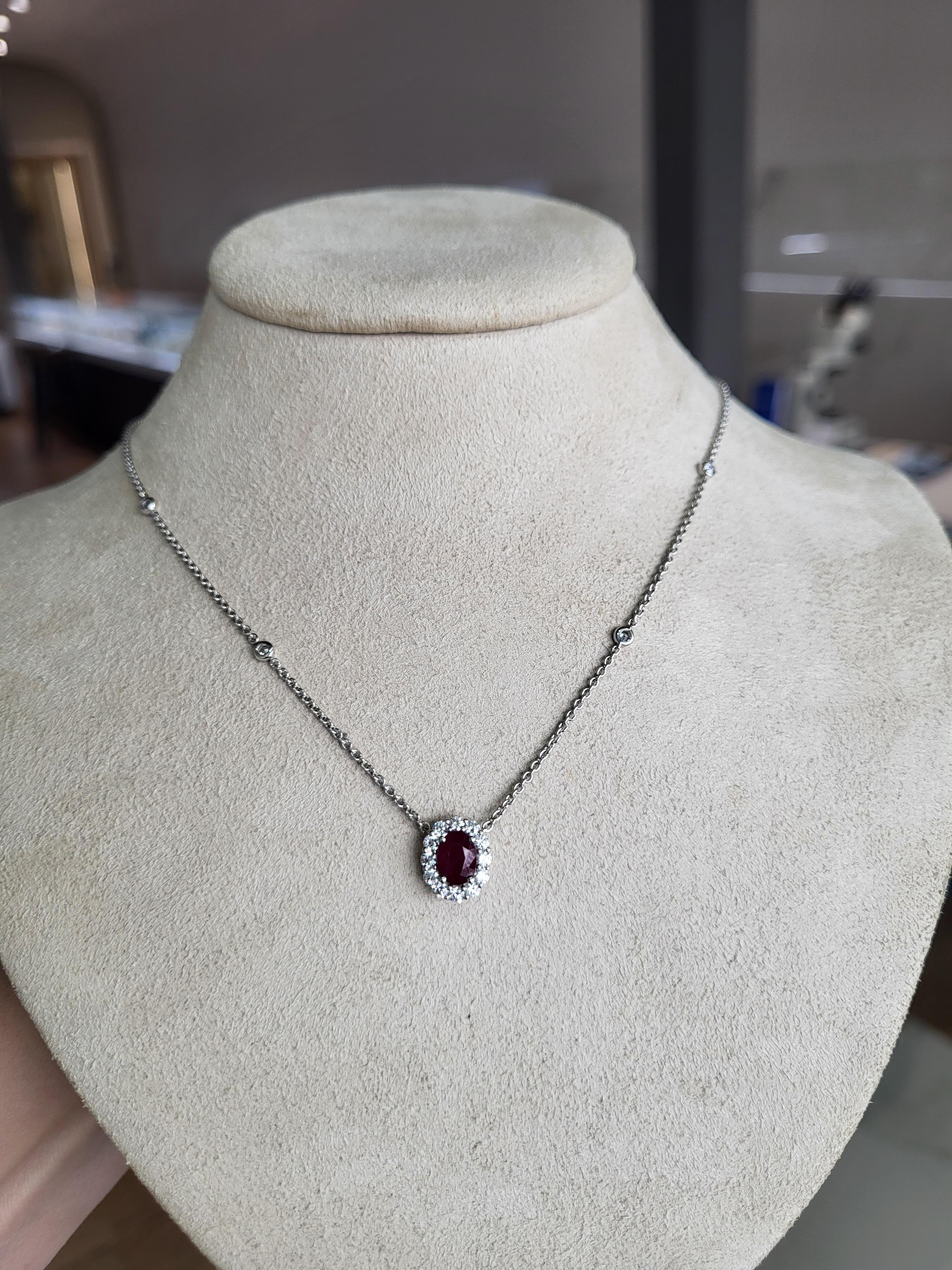 This beautiful pendant necklace features a 0.71 carat natural ruby accented by 0.48 carat total weight in round diamonds set in 18 karat white gold. The pendant is set on a diamond by the yards style chain. 
Measurements: Length 18