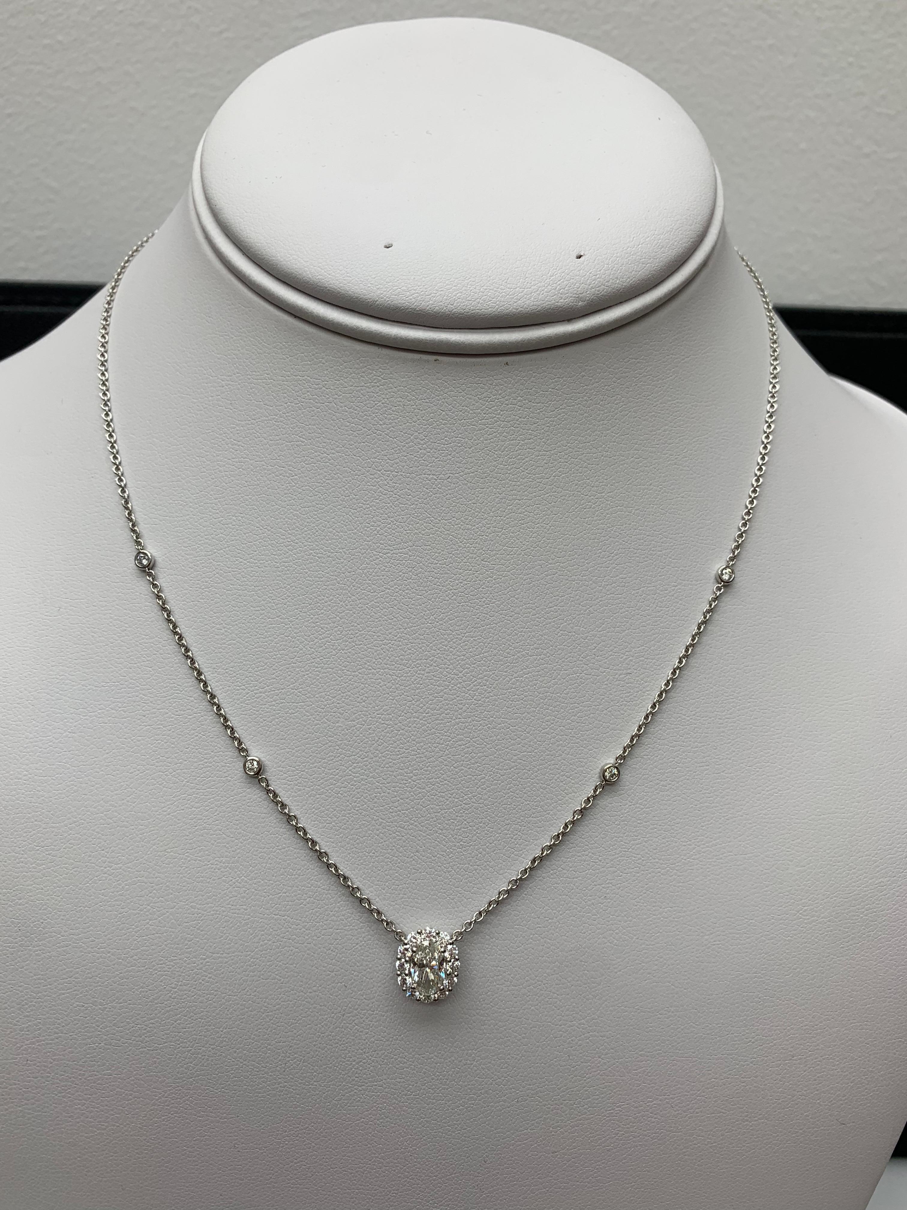 Un collier pendentif à la mode mettant en valeur un rubis ovale de 0,71 carat. La pierre centrale est entourée d'une rangée de 16 diamants ronds de taille brillant pesant 0,48 carats au total. Fabriqué en or jaune 14k. Il est accompagné d'une chaîne