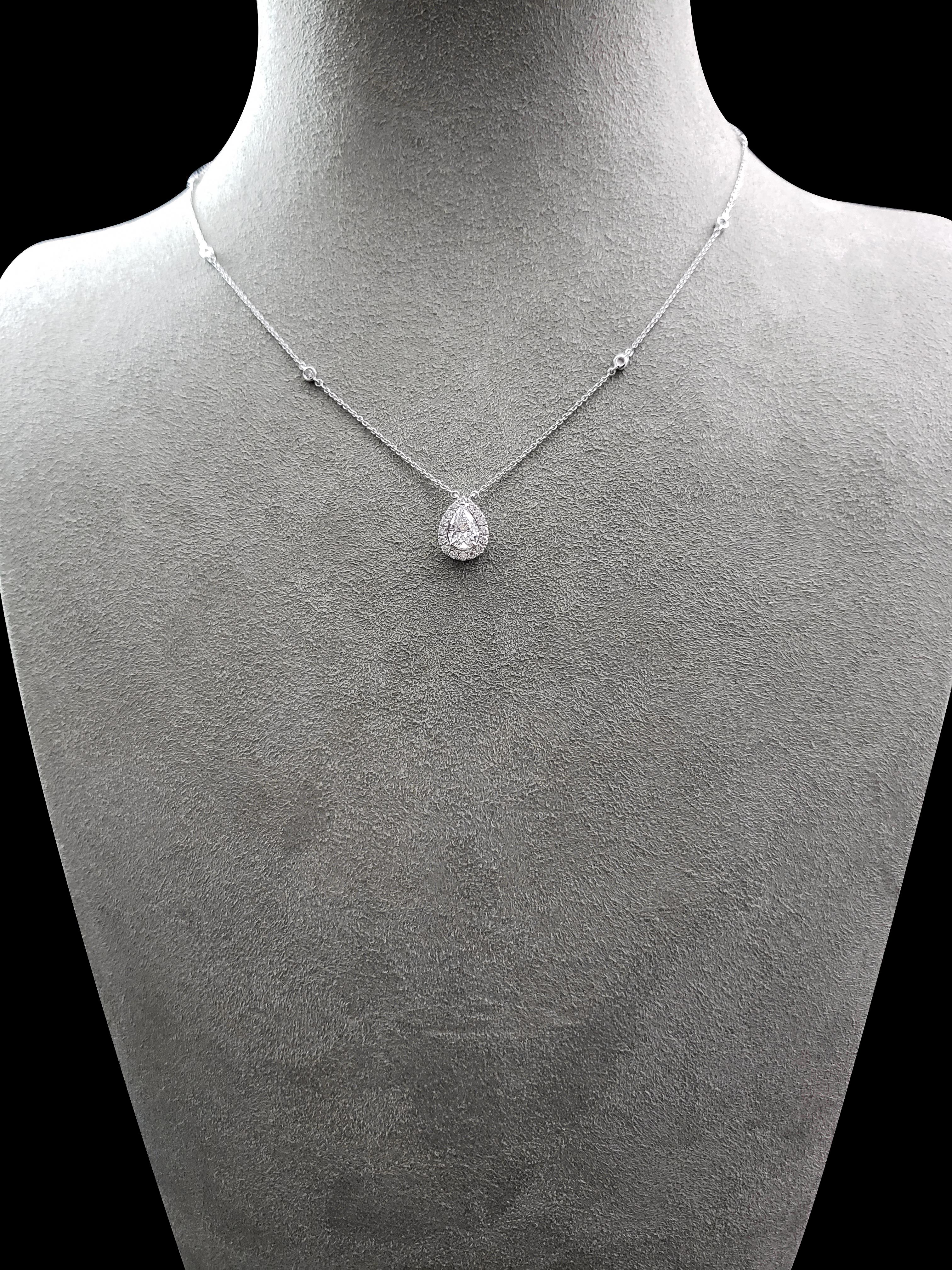 A luxurious and brilliant pendant necklace set with a gorgeous 0.72 carat pear shape diamond. The center diamond is surrounded by a halo of round brilliant diamonds set in an 18 karat white gold composition. Attached to an adjustable 16-18 inch