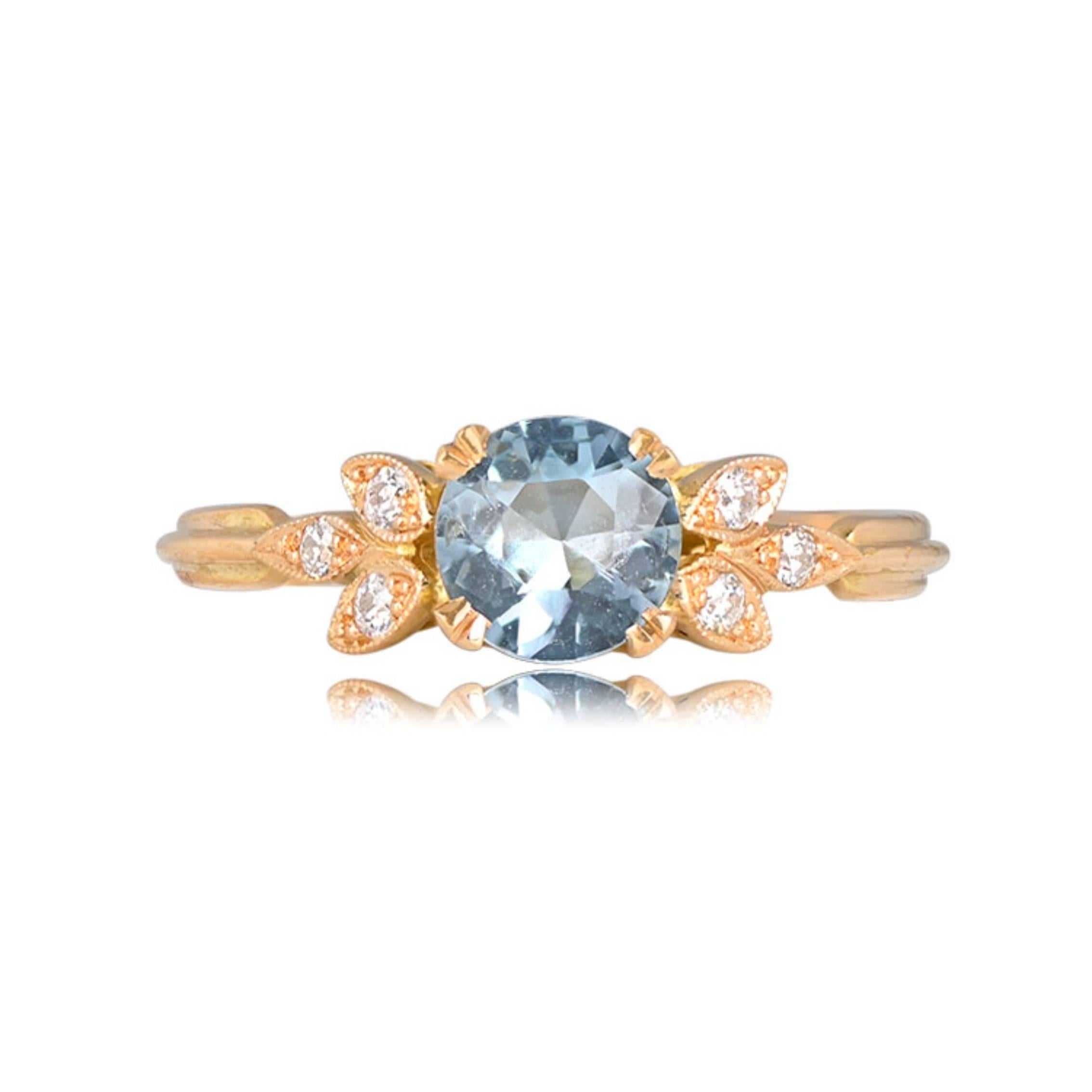 This 18k yellow gold gemstone engagement ring showcases a 6mm round aquamarine securely set in prongs, with the shoulders adorned by a leaf design featuring old European cut diamonds. The central aquamarine weighs about 0.72 carats. This ring has a