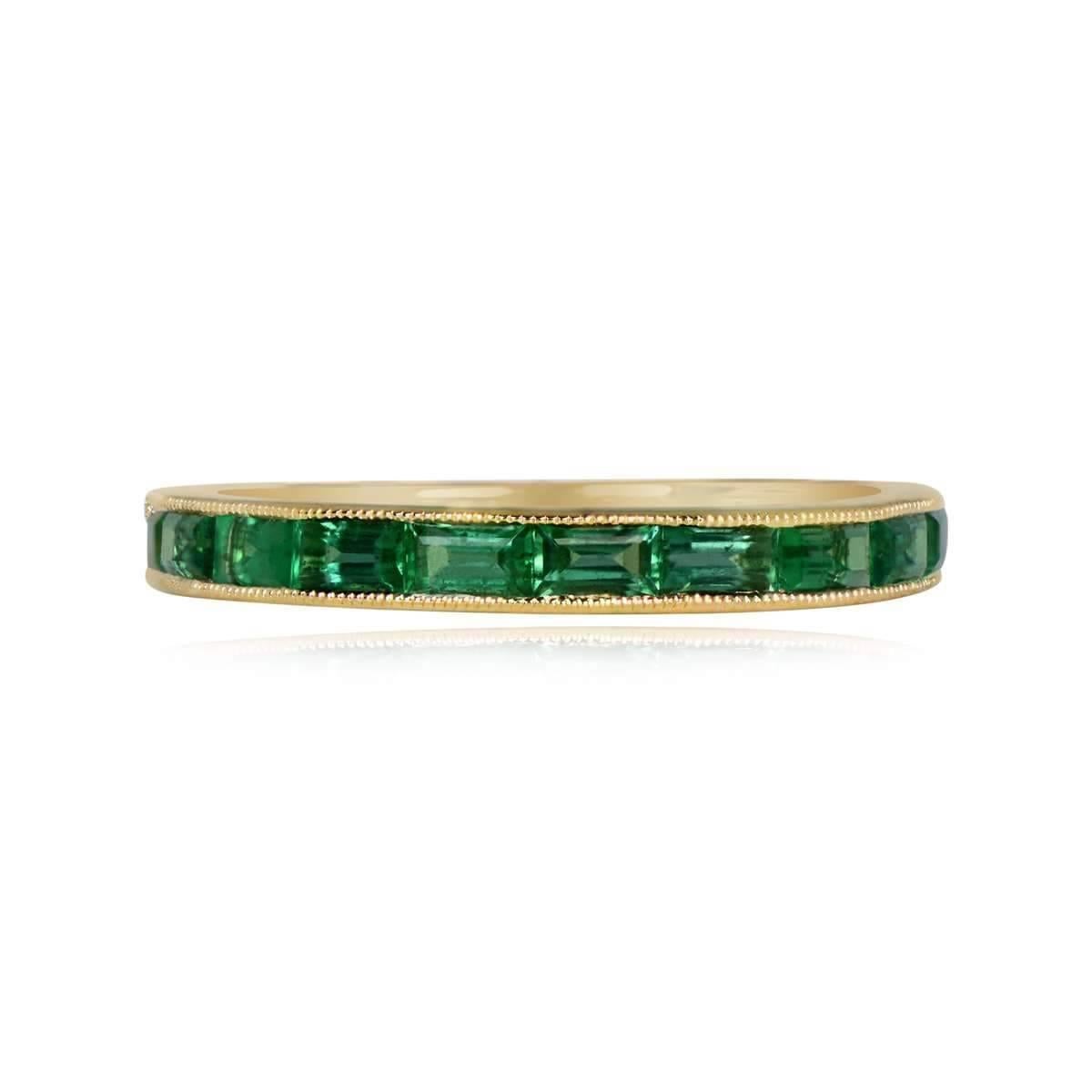 A stunning half-eternity band in 18k yellow gold, featuring natural baguette-cut green emeralds set east-west with a total weight of approximately 0.73 carats. The emeralds are channel-set and adorned with fine milgrain detailing around the bezels.