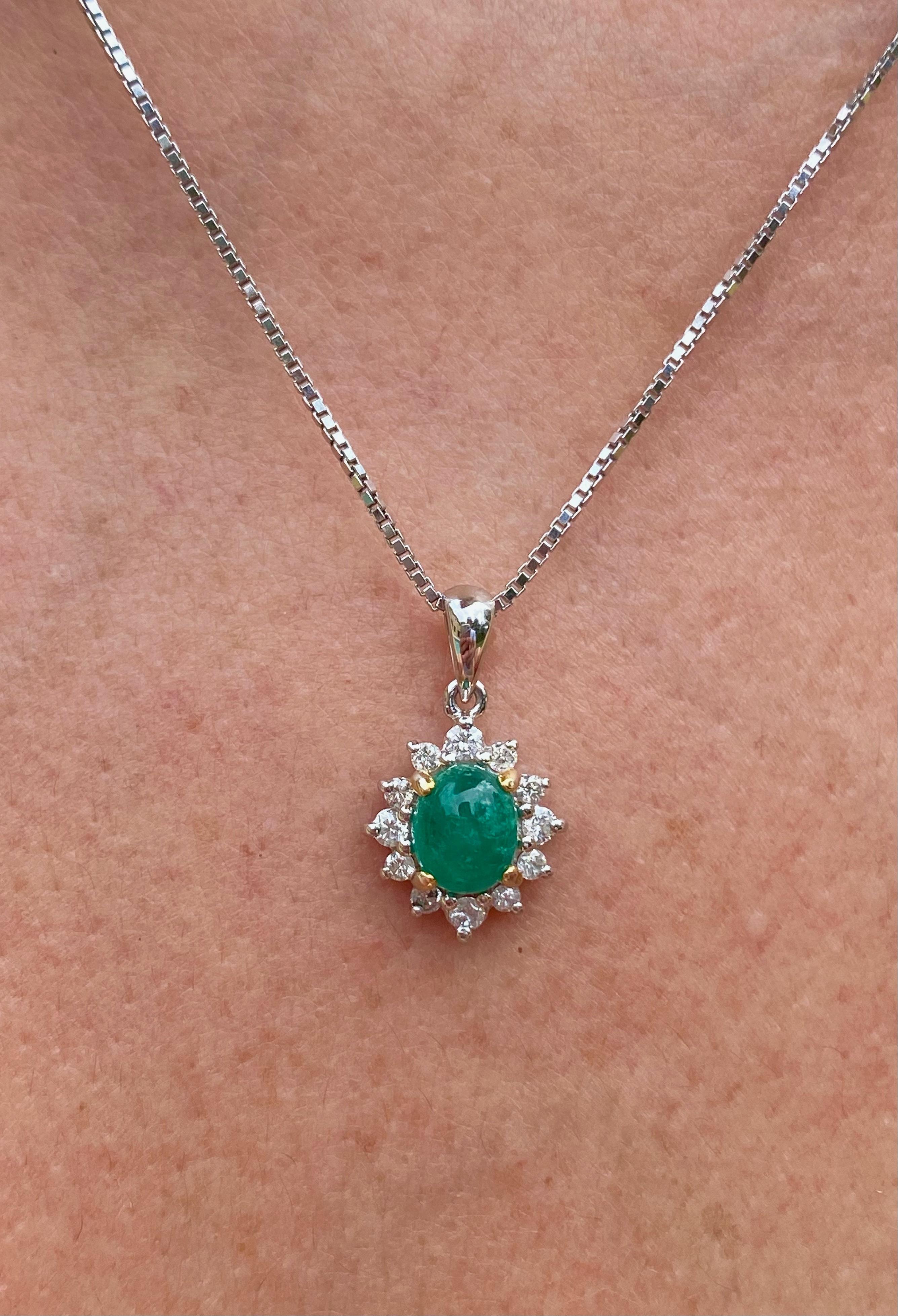Centering a 0.74 Carat Oval-Cut Colombian Emerald, framed by 12 Round-Brilliant Cut Diamonds totaling 0.20 Carats, and set in 18K White Gold. 
Natural Emerald Pendant of Colombian origin. Cabochon-Cut center stone with a vibrant vivid green color