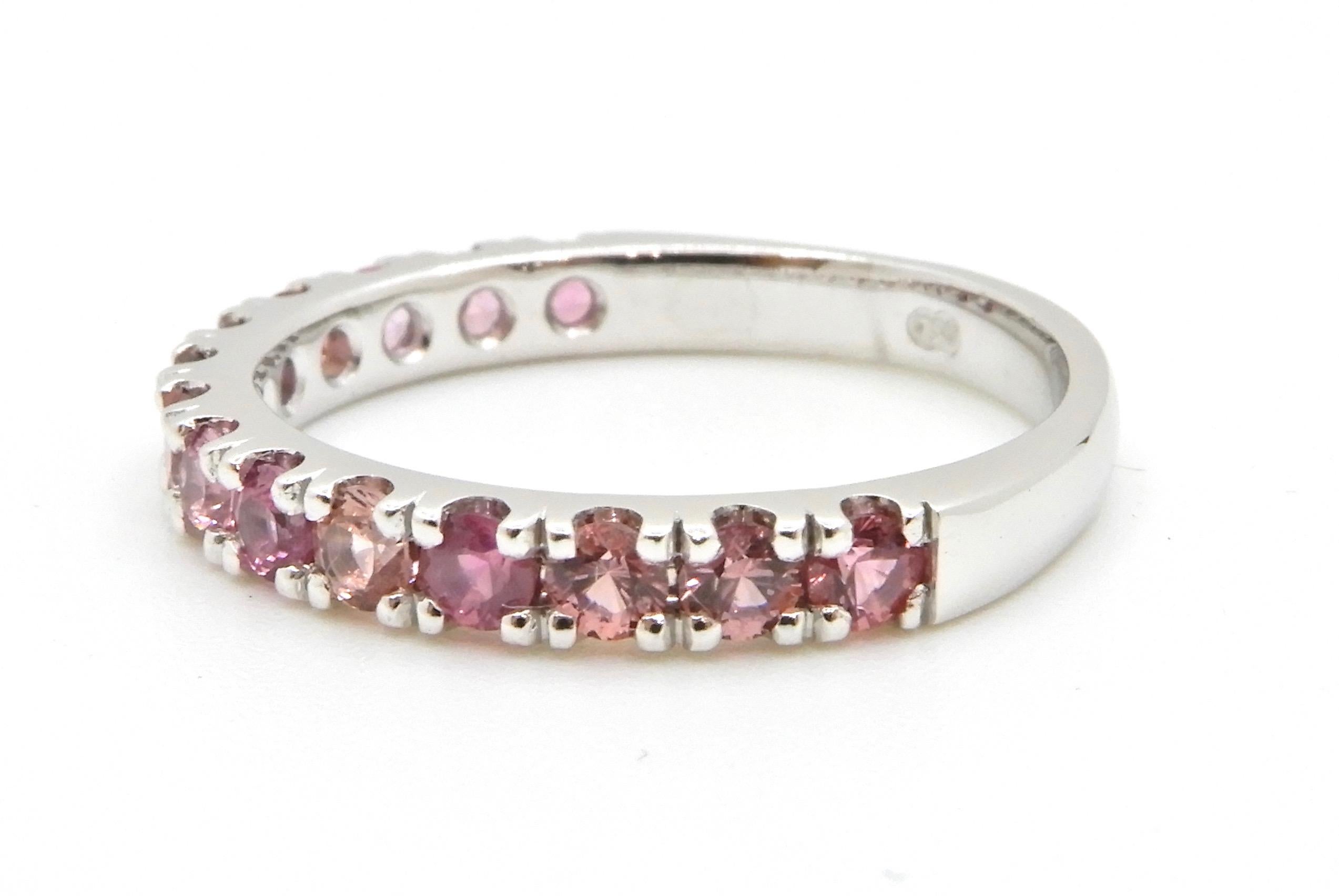 This 0.74 Carat Pink Sapphire and 18 Carat White Gold Wedding Ring is made in the half eternity band style. Set with 14 x 2.5mm round brilliant cut natural, no heat pink sapphires in varying shades.

The design features a wide round, tapered shank