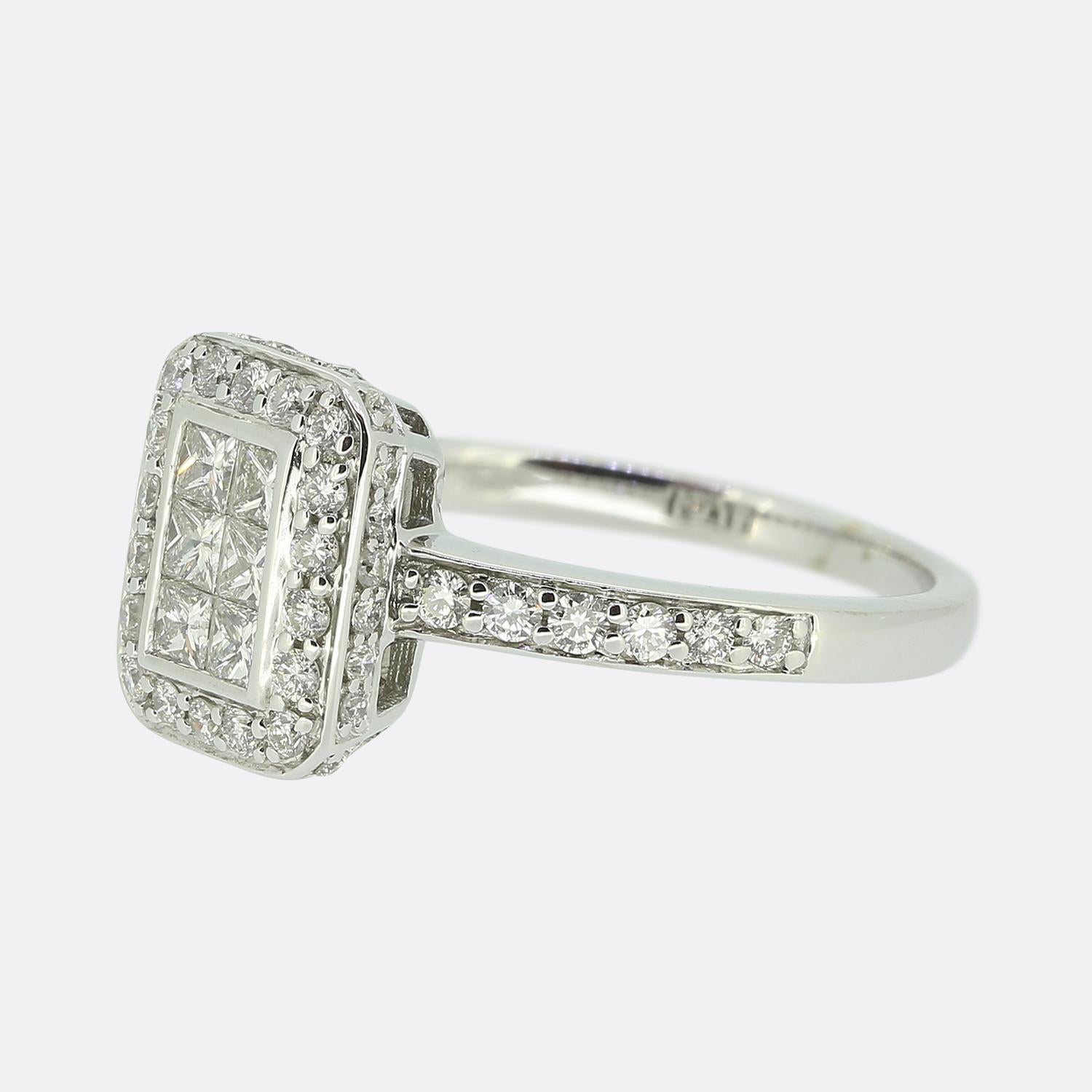 Hier haben wir einen Diamantring aus 18 Karat Weißgold mit Pavé-Fassung. Der Ring ist mit 6 unsichtbar gefassten Diamanten im Prinzessinnenschliff besetzt, die von 18 runden Diamanten im Brillantschliff eingefasst sind. Außerdem befinden sich auf