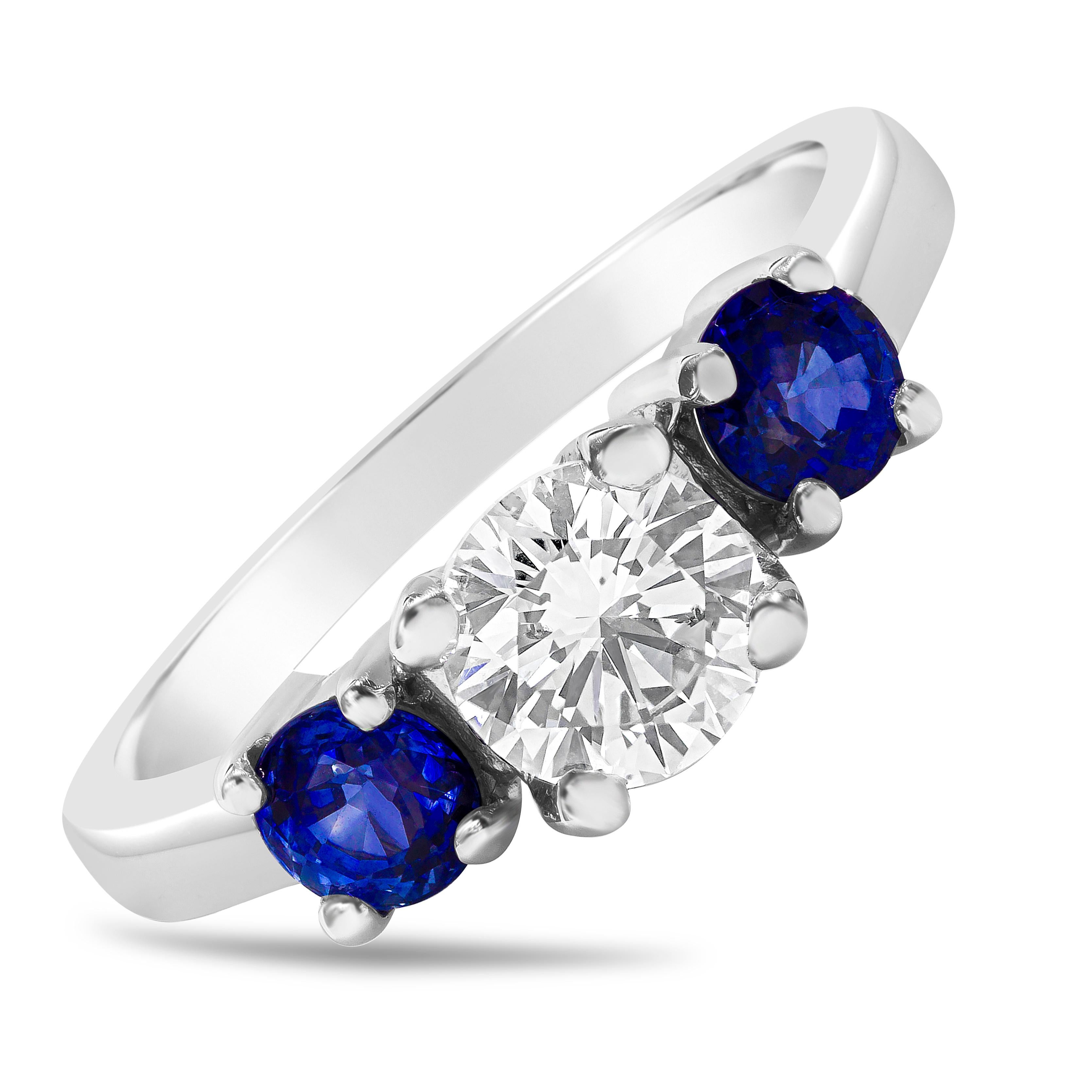 This simple and beautiful three stone engagement ring features a 0.74 carats round brilliant diamond center stone that GIA certified as D color, SI2 in clarity; flanked by two vibrant blue sapphires on each side weighing 0.82 carats total. Set in a
