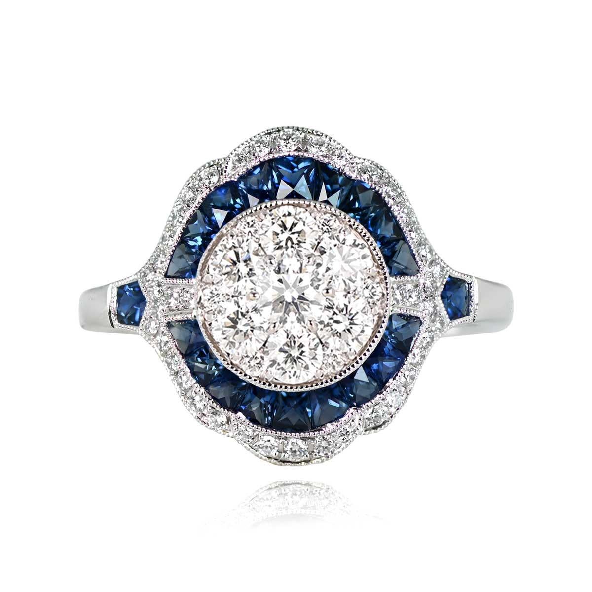 A mesmerizing Art Deco-style platinum ring adorned with a captivating array of sapphires and diamonds. The central focus is a cluster of round brilliant-cut diamonds, encircled by a double halo composed of natural blue French-cut sapphires and