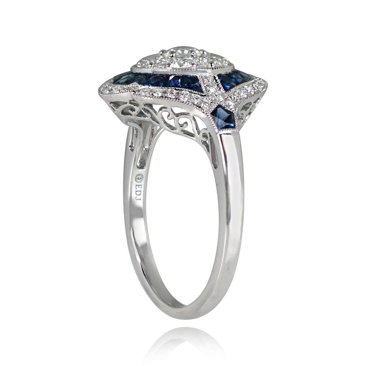 An exquisite Art Deco-style platinum ring adorned with a cluster of round brilliant-cut diamonds at the center. A double halo of natural blue French-cut sapphires and diamonds surrounds the centerpiece. This ring boasts a low-profile design.

Ring