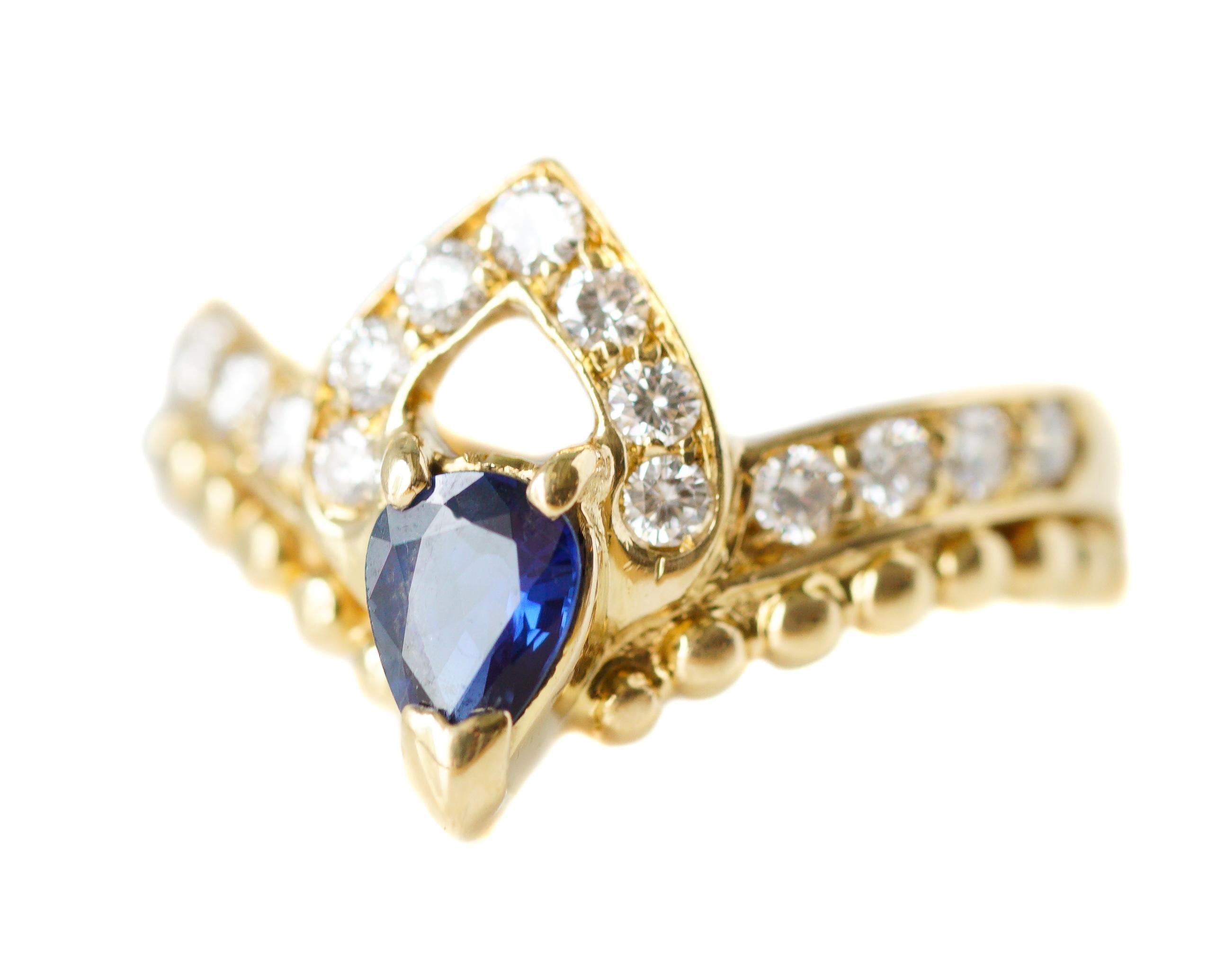 This elegant Vintage ring features a 0.25 carat Pear Cut Blue Sapphire with 0.75 carat total sparkling Round Brilliant Diamonds.

The 18 karat Yellow Gold richly accents the prong set gemstones. A modified Diamond half halo crowns the Blue Sapphire