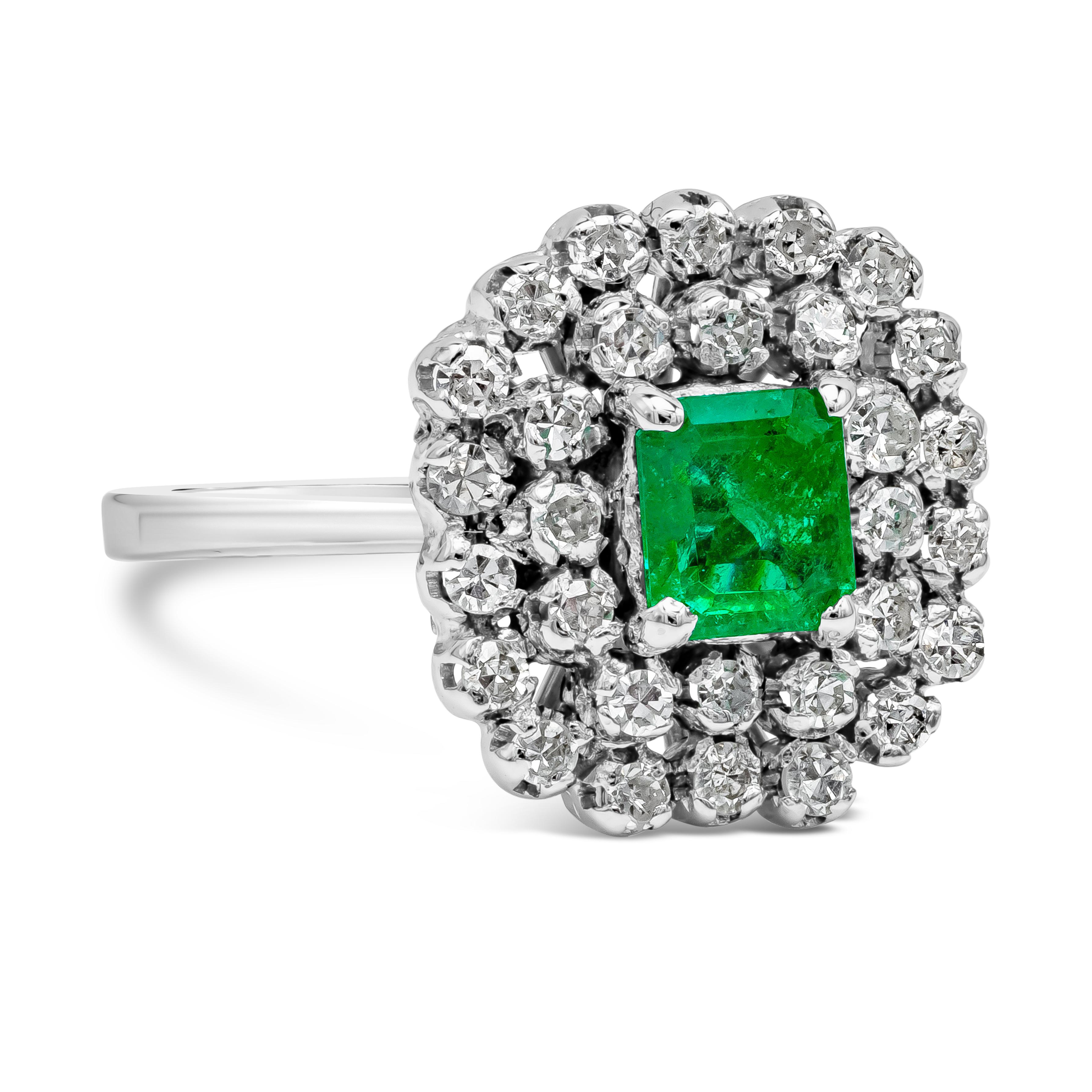 A beautiful antique ring, showcasing a 0.75 carat emerald cut green emerald set on a four prong setting. Surrounded by single cut round diamonds arranged in a cluster style weighing 0.30 carat total. Made with 14K white gold. Size 6.25 US, resizable