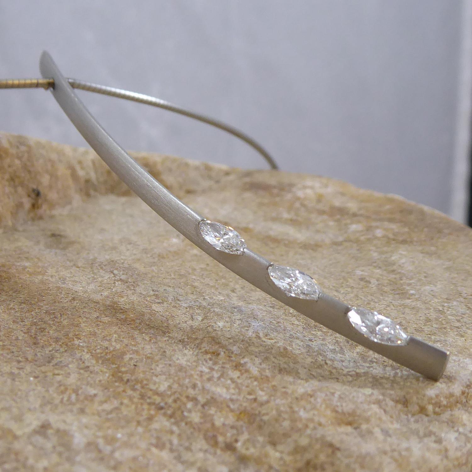A very avant-guarde diamond pendant from the UK jewellery designer, Paul Spurgeon.  A curved, knife-edge top, platinum bar set with three marquise cut diamonds invisibly tension set to the lower half of the bar.  The diamond combine to give a total