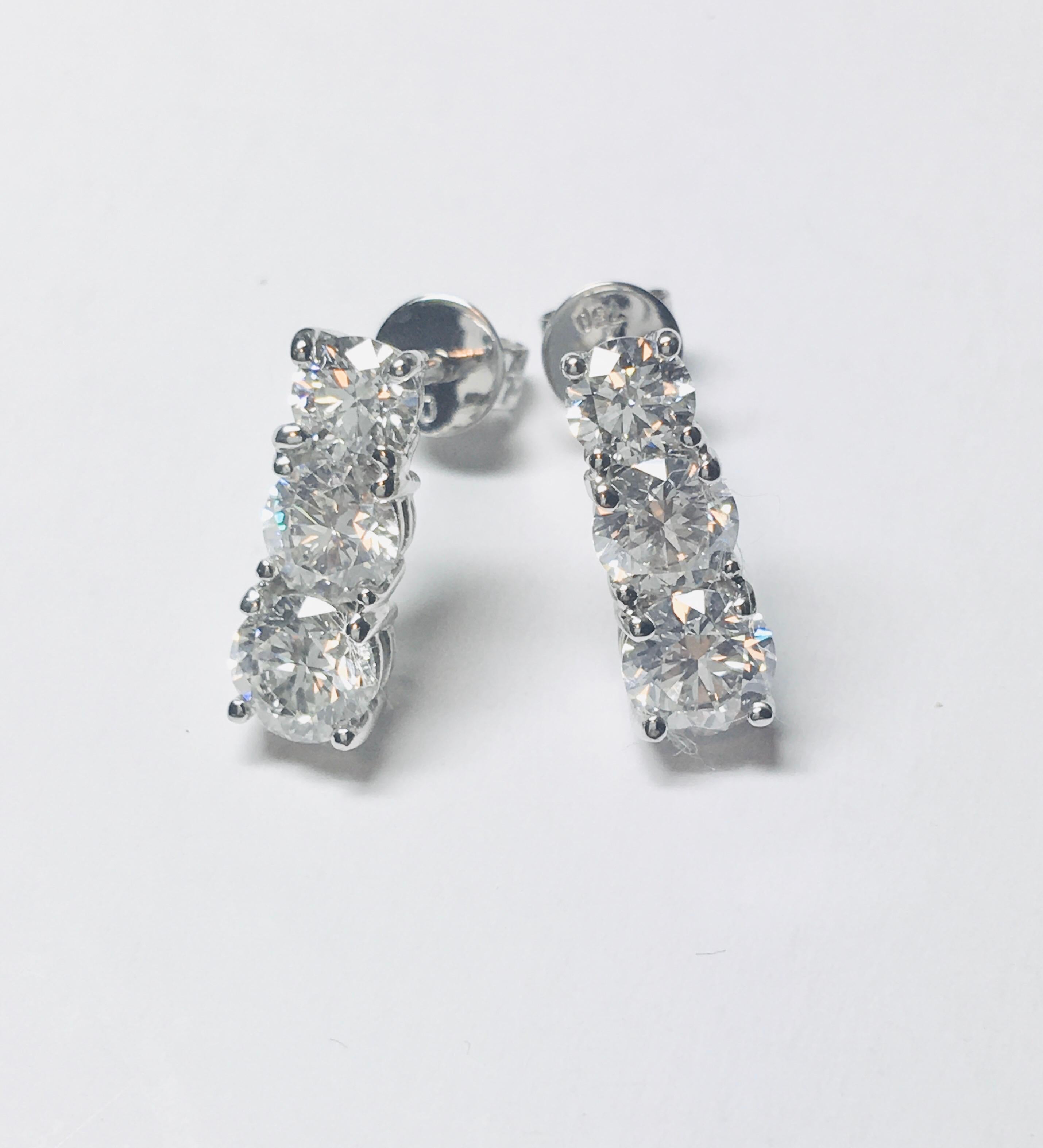 Classy understated Pair of graduated round brilliant cut three-stone diamond drop earrings, featuring a total of 0.75 carat diamond colour G/H clarity SI, each stone is set in a classic 4 claw mount with post and butterfly fittings, all set in 18