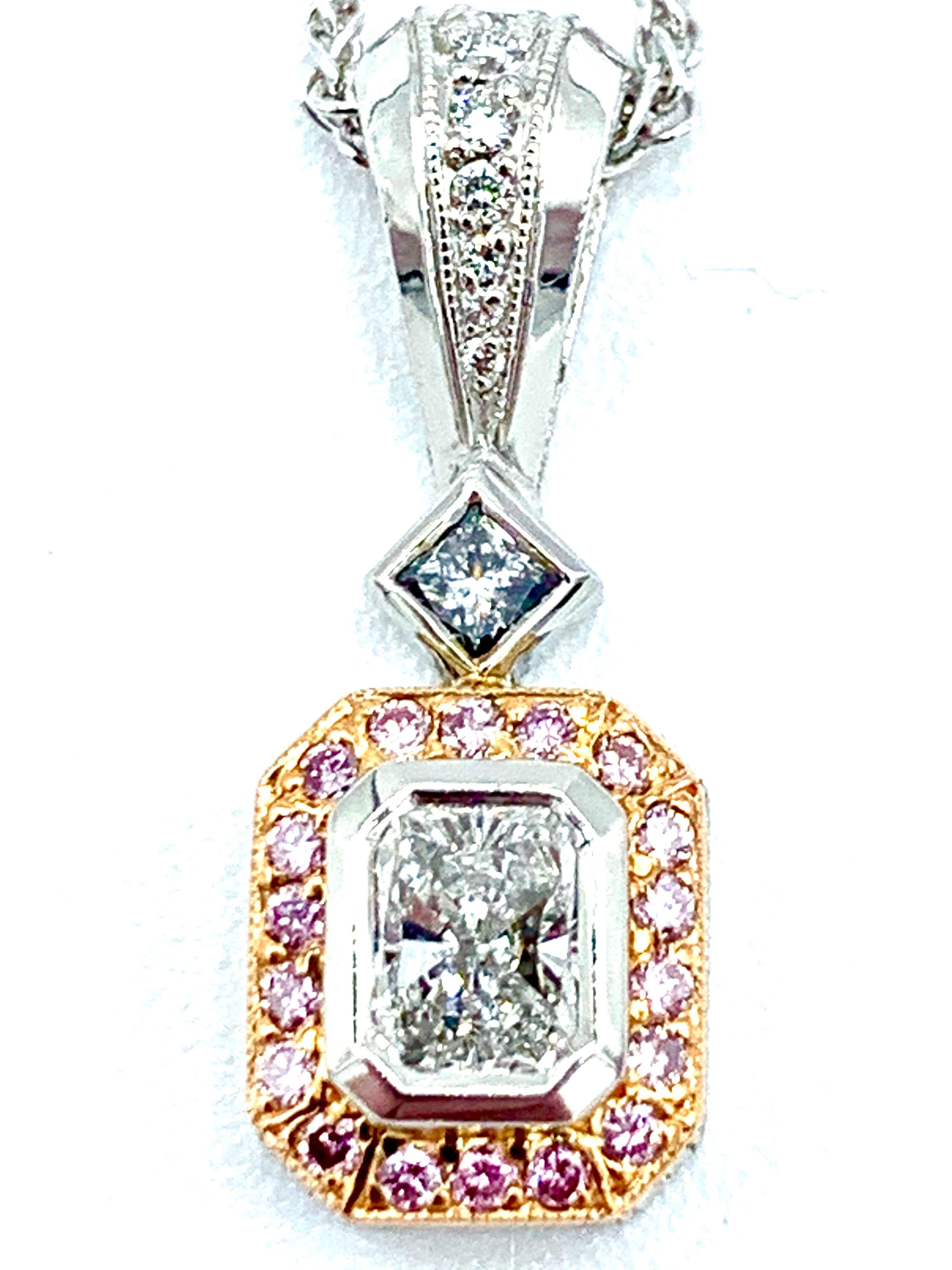 A gorgeous handcrafted white and pink Diamond and platinum pendant.  The center bezel set radiant cut Diamond is 0.50 carats, surrounded by a single row of round brilliant pink Diamonds, and suspended from a princess cut Diamond and Diamond bale. 
