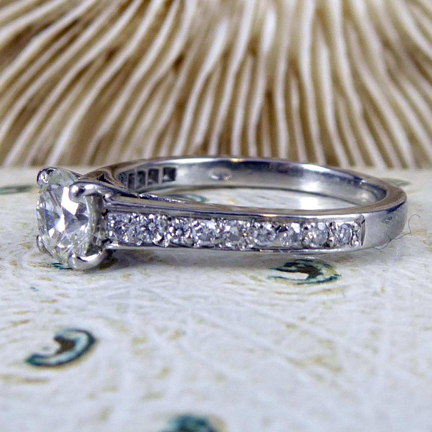 A pre-owned, modern single stone diamond soliaire ring claw set in platinum to diamond set shoulders and a plain platinum 