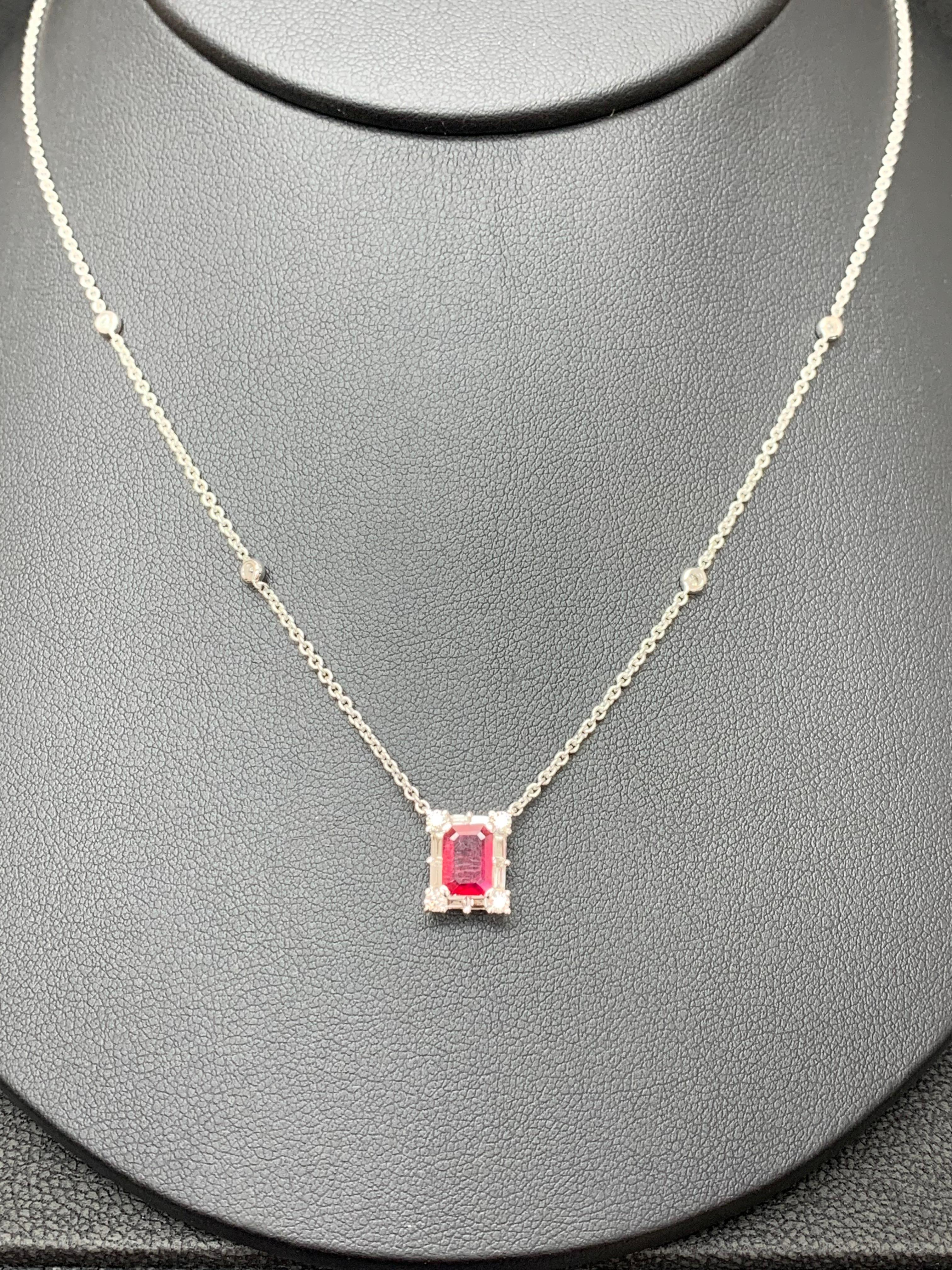 A fashionable pendant necklace showcasing a 0.77-carat emerald cut vibrant red color Ruby. The center stone is surrounded by a row of brilliant-cut 8 round and 8 baguette diamonds weighing 0.58 carats total. Made in 18k white gold. Comes with a gold