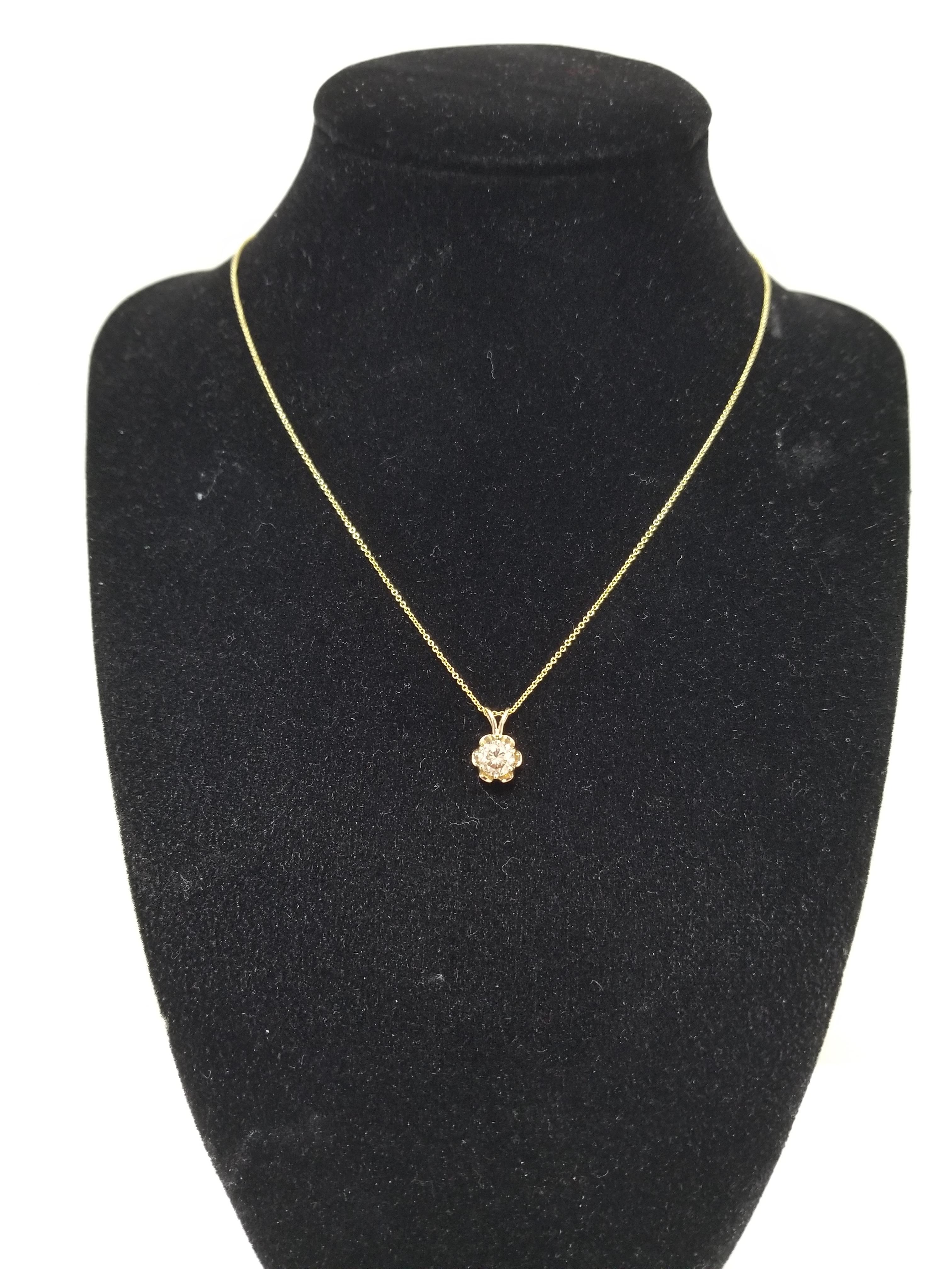 This gorgeous diamond pendant features a 0.77 carat champagne cognac color round diamond solitaire set in a beautiful 14 karat yellow gold buttercup design. Pendant measures approximately 0.5 inch length and 0.25 inch wide. 

(Pendant Only - Chain