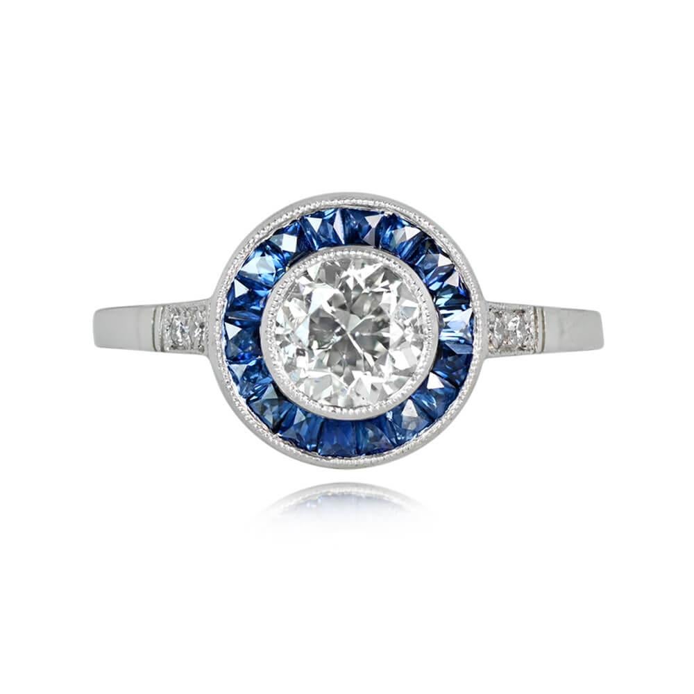 A captivating diamond and sapphire halo ring features a 0.77-carat old European cut diamond at its center, with J color and SI2 clarity. The center diamond is gracefully bezel-set and complemented by a halo of calibre French-cut sapphires, weighing