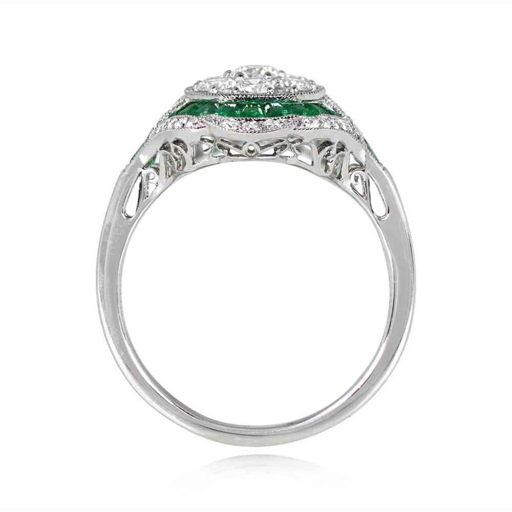 This ring features a cluster of round brilliant cut diamonds in the center, H color, and VS1-VS2 clarity overall. The diamonds are surrounded by a double halo of caliber cut emeralds and additional round brilliant cut diamonds. A single