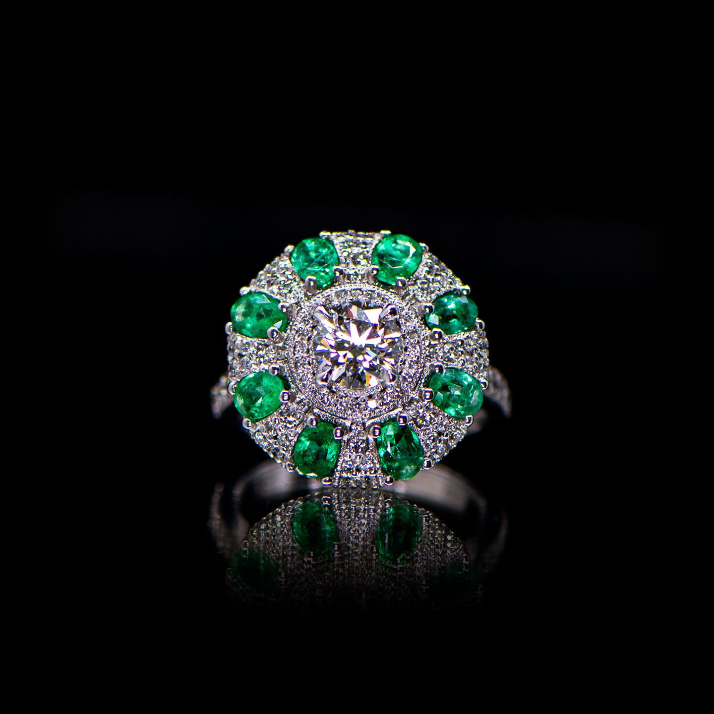 This eternally glamorous, ready-to-wear French Art Deco style ring features eight luminous oval cut emeralds radiating from a dazzling central diamond. Each stone is nestled in an exquisitely handcrafted pavé diamond milgrain cluster setting,