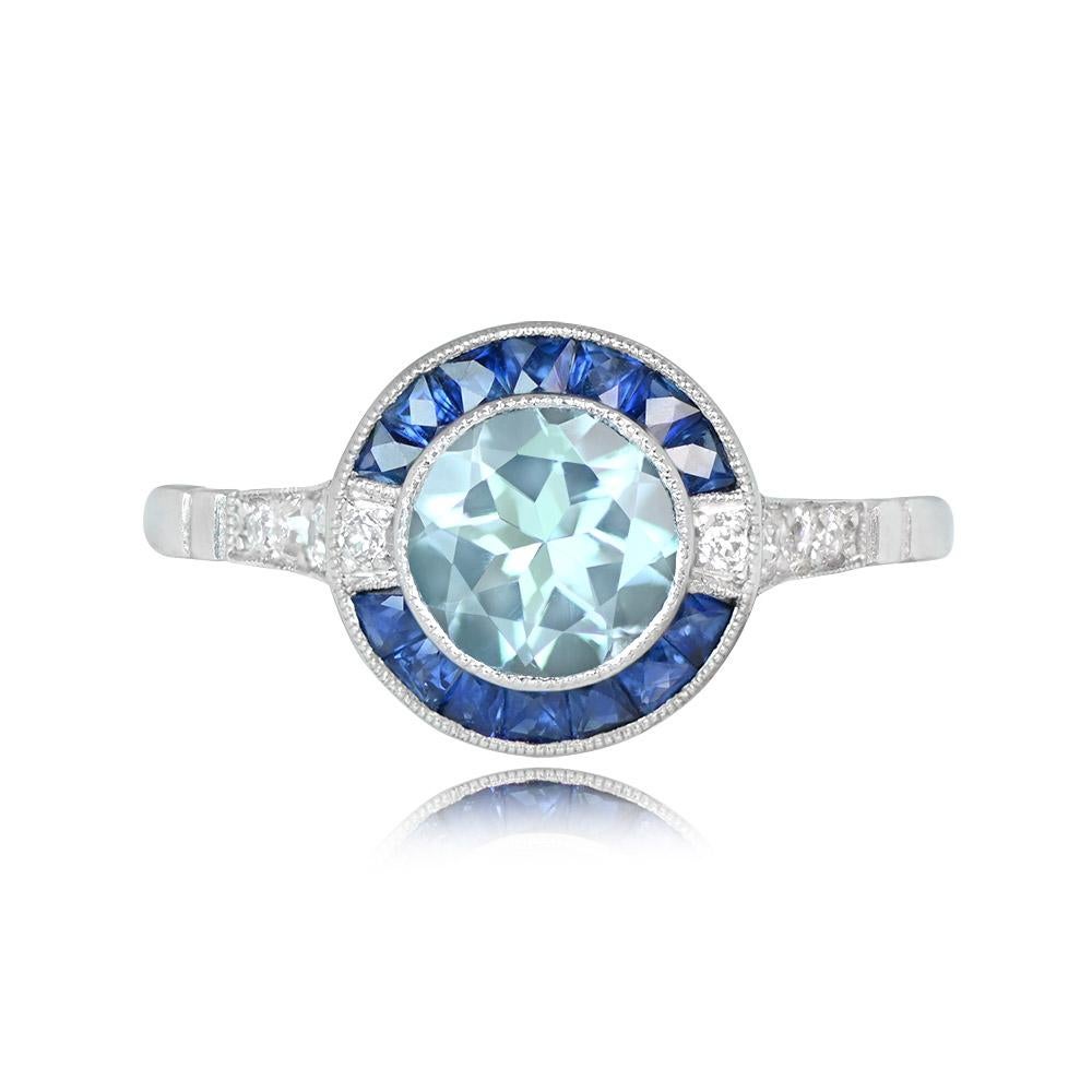 This ring features a 0.78-carat aquamarine, haloed by French-cut sapphires totaling about 0.42 carats. Old European cut diamonds, approximately 0.13 carats in weight, adorn the sides. Crafted in platinum, this ring boasts an openwork
