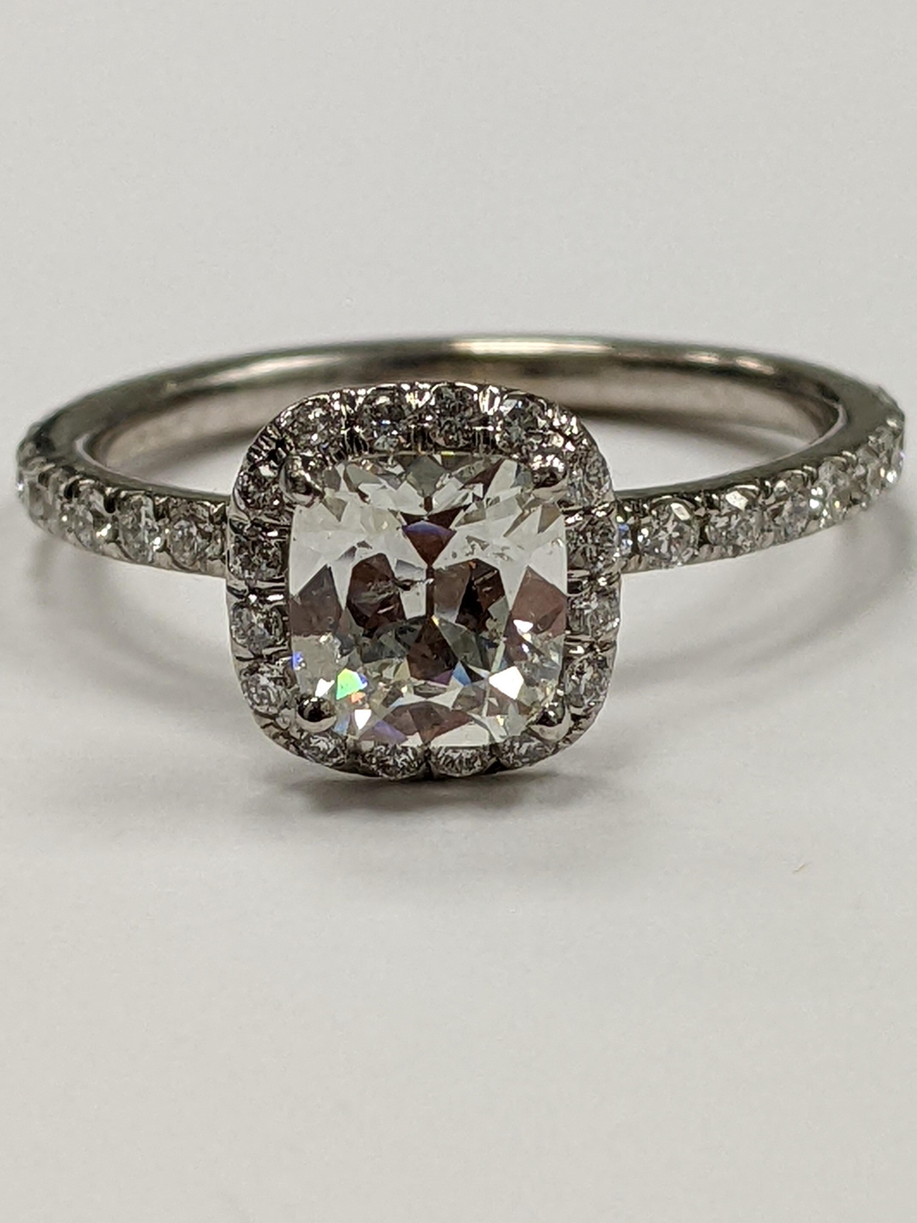 0.82 Cushion in G color SI-2 clarity (AGS certificate upon request) mounted in a simply elegant ring.  The mounting is made out of 18KT white gold, and the center stone is surrounded by a halo of small diamonds that extends into the shank as well