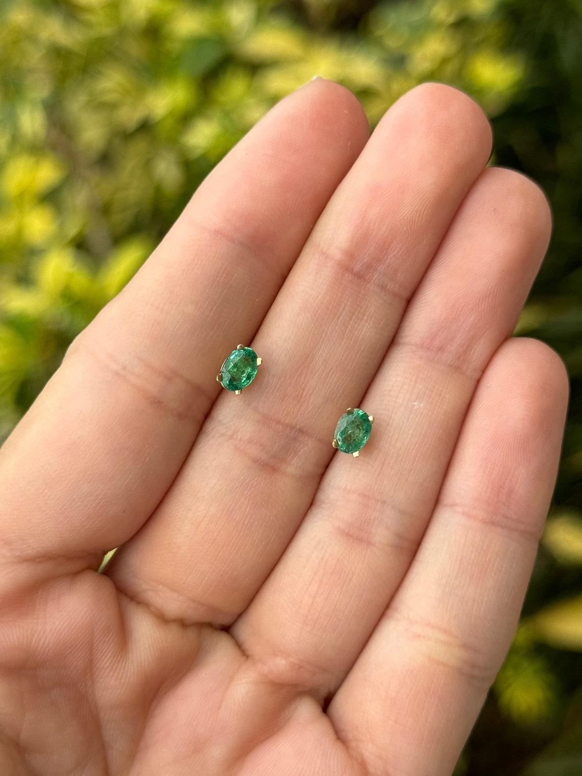 Elevate your ensemble with our captivating emerald stud earrings, featuring two oval-cut emeralds totaling 0.80 carats. Set in a refined four-prong setting crafted from luminous 14k yellow gold, these earrings showcase the rich green hue and