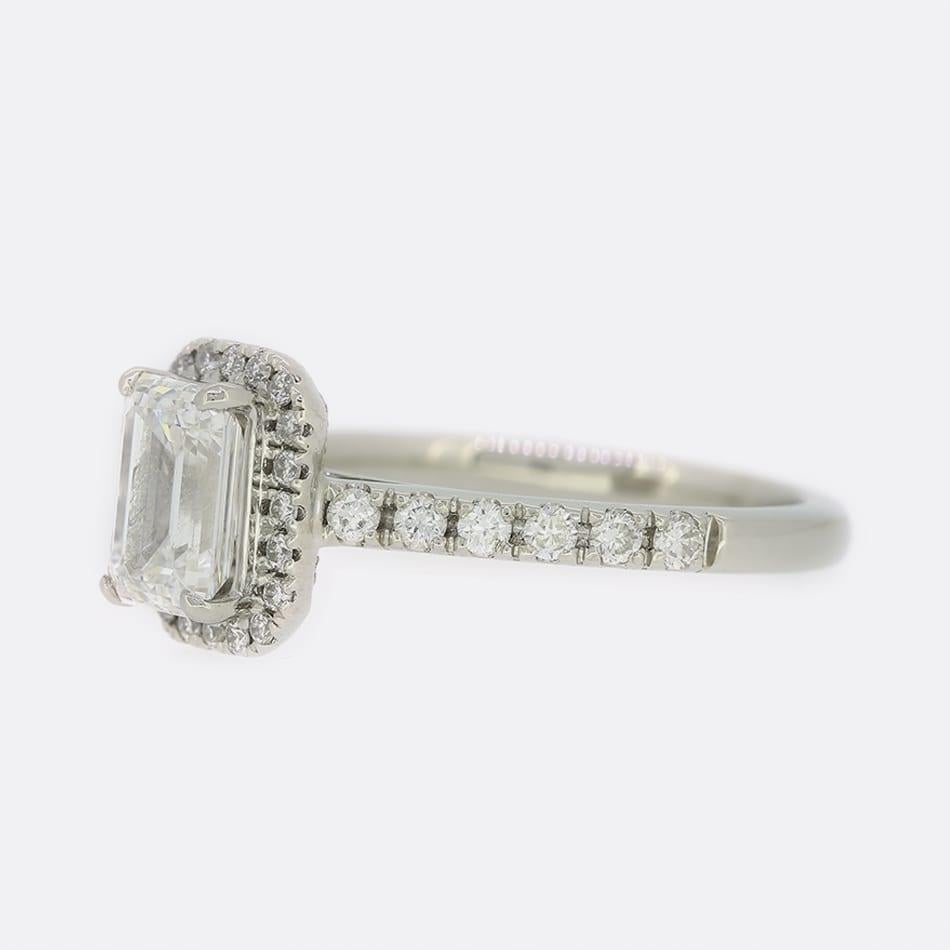 This is a platinum diamond engagement ring. The focal point of this ring is a GIA certified 0.81 carat emerald cut diamond with a border 18 smaller diamonds and a further 6 on each shoulder.

Condition: Used (Very Good)
Weight: 3.6 grams
Size: H