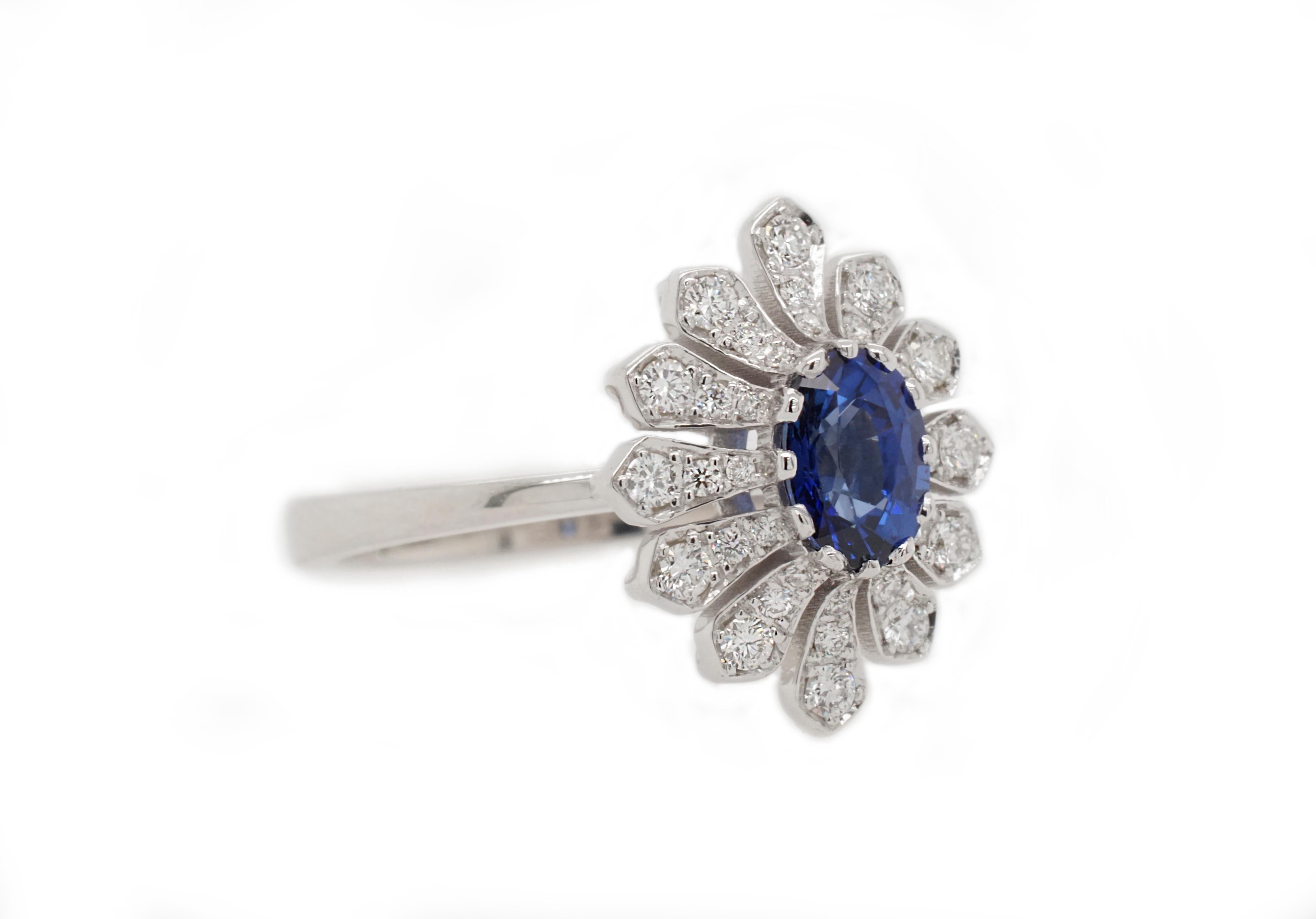 This beautiful ring flaunts a 0.84 carat oval-cut natural deep blue Sapphire. White round brilliant diamonds are set on the petals surrounding it, creating an Art Deco-inspired flower shape. 

Set in 14K white gold. 

Center stone: Natural heated