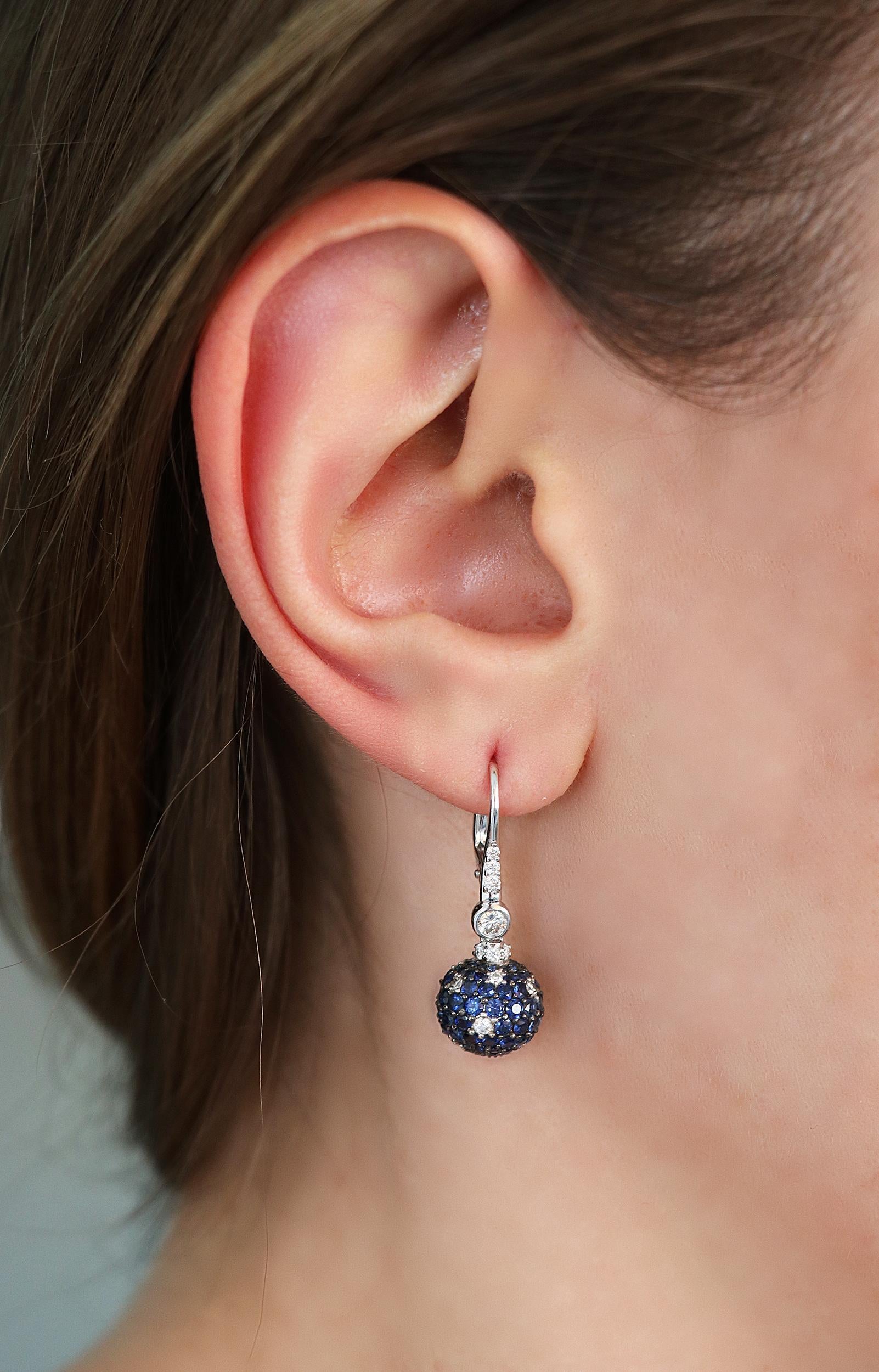 Ball shaped pendant earrings with 0.84 carats of round white diamonds and 4.24 carats of round cut blue sapphires. 
The weight of 18kt white gold is 4.70 grams. 
The earring has a total length of 3.00cm and the pendant has a diameter of