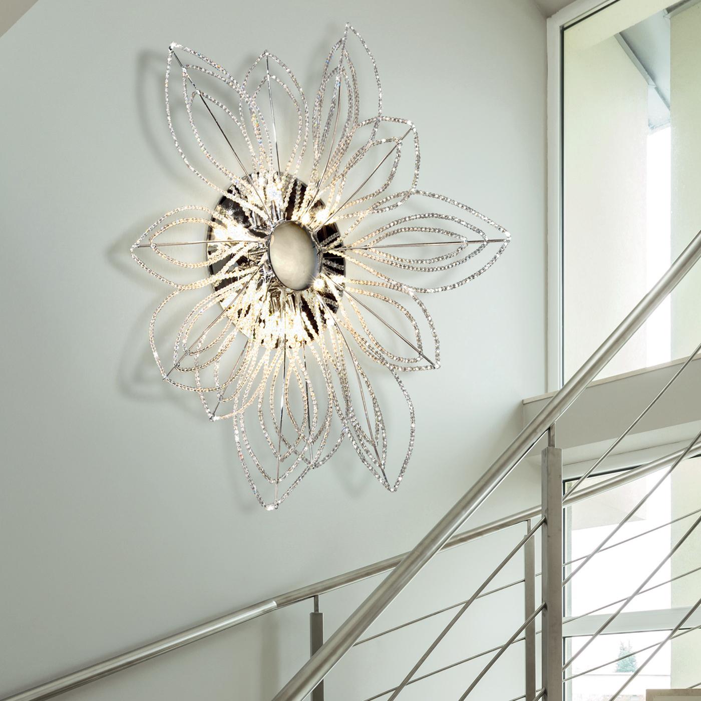 Crafted in transparent crystal with the main structure in a chrome or gold finish, this beautiful ceiling lamp features an elaborate and perfectly charming design. In the form of a flower and holding 12 lamps, the lighting fixture offers an element