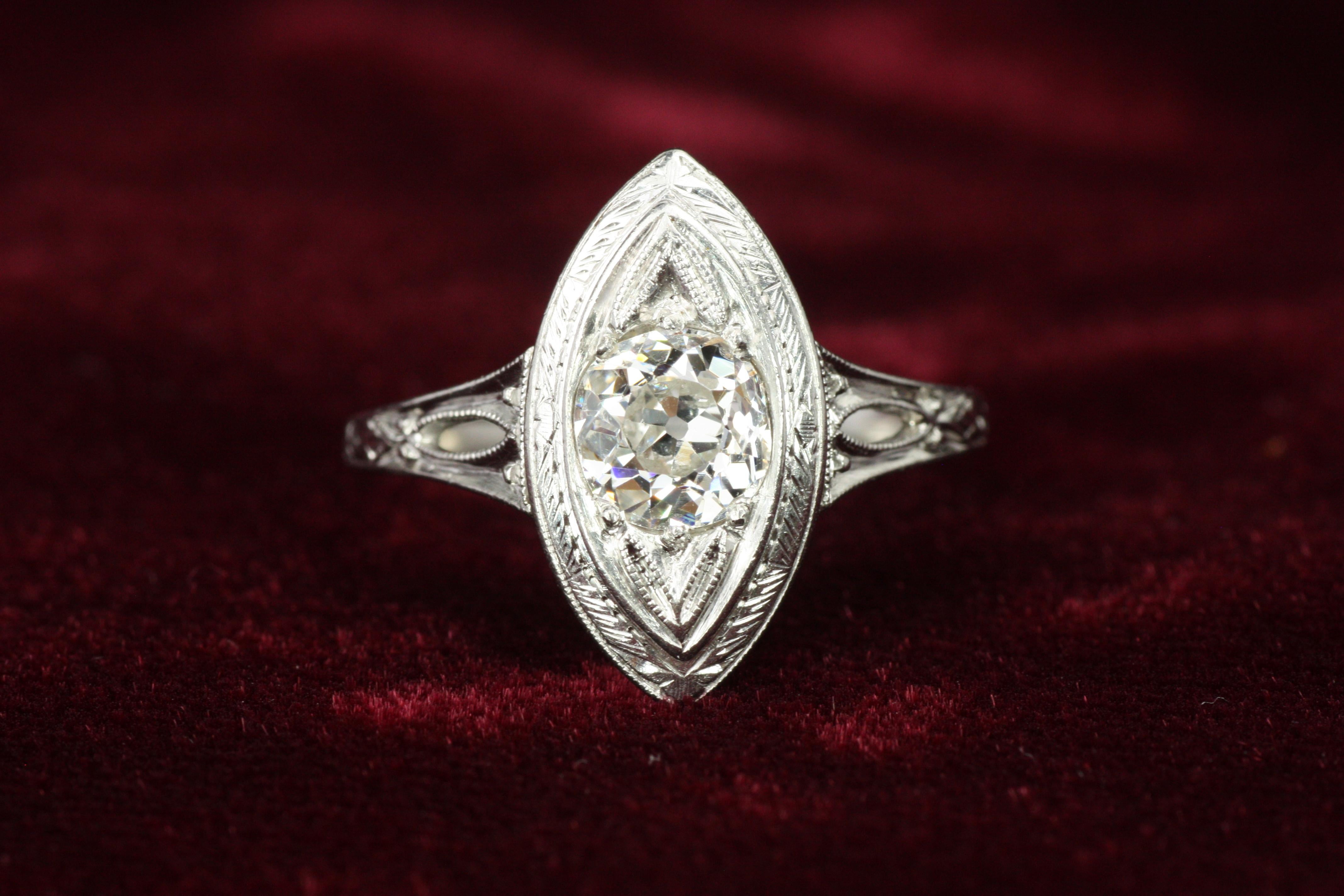 This delicate 1920s Art Deco engagement ring features a beautiful 0.85ct Old Mine cut antique natural diamond set in an intricately crafted platinum filigree design. With unique shank cut-out details and intricate milgrain accents, this ring is a