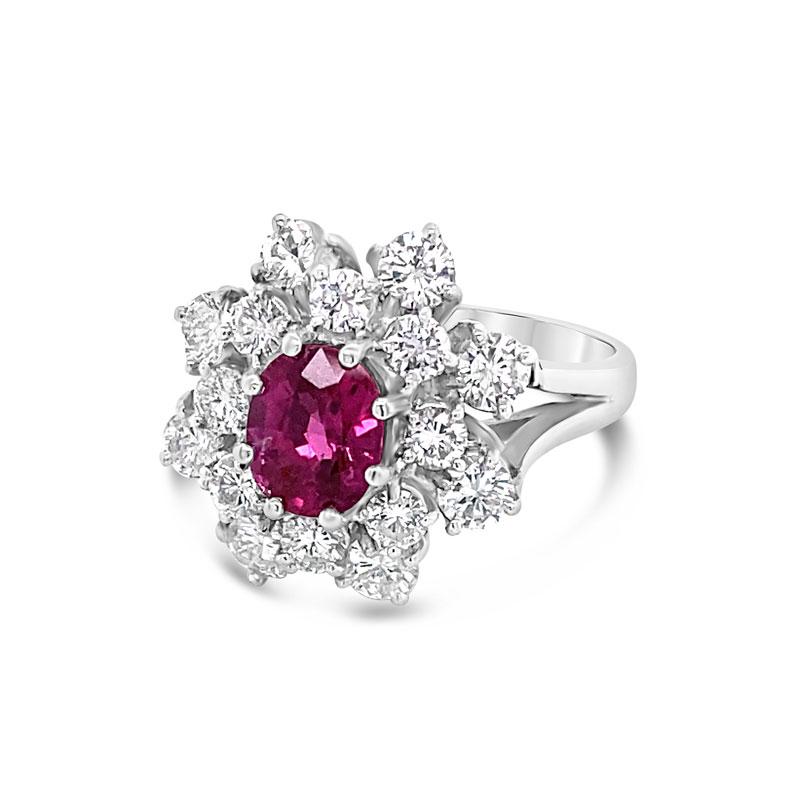 A beautiful cocktail ring feature a 0.85 carat oval cut ruby surrounded by 2.50 carat total weight in round diamonds set in 18 karat white gold. This ring is a size 6 but can be resized upon request.