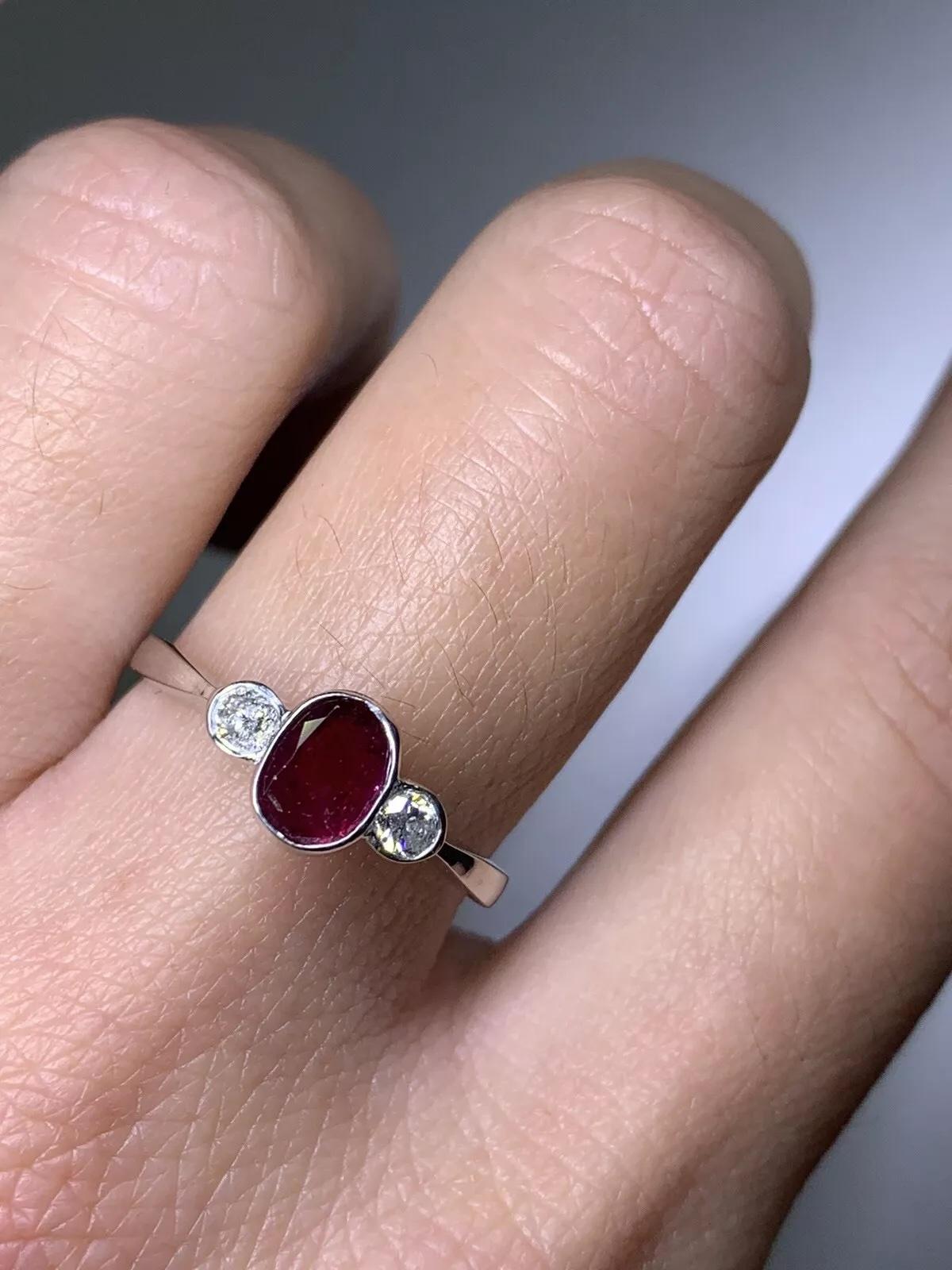 Questo splendido anello di fidanzamento in stile antico è una vera meraviglia del design. Realizzato in oro bianco 9ct, presenta un bellissimo rubino rotondo come pietra principale, circondato da 0,85 carati di diamanti e rubini naturali. L'anello è