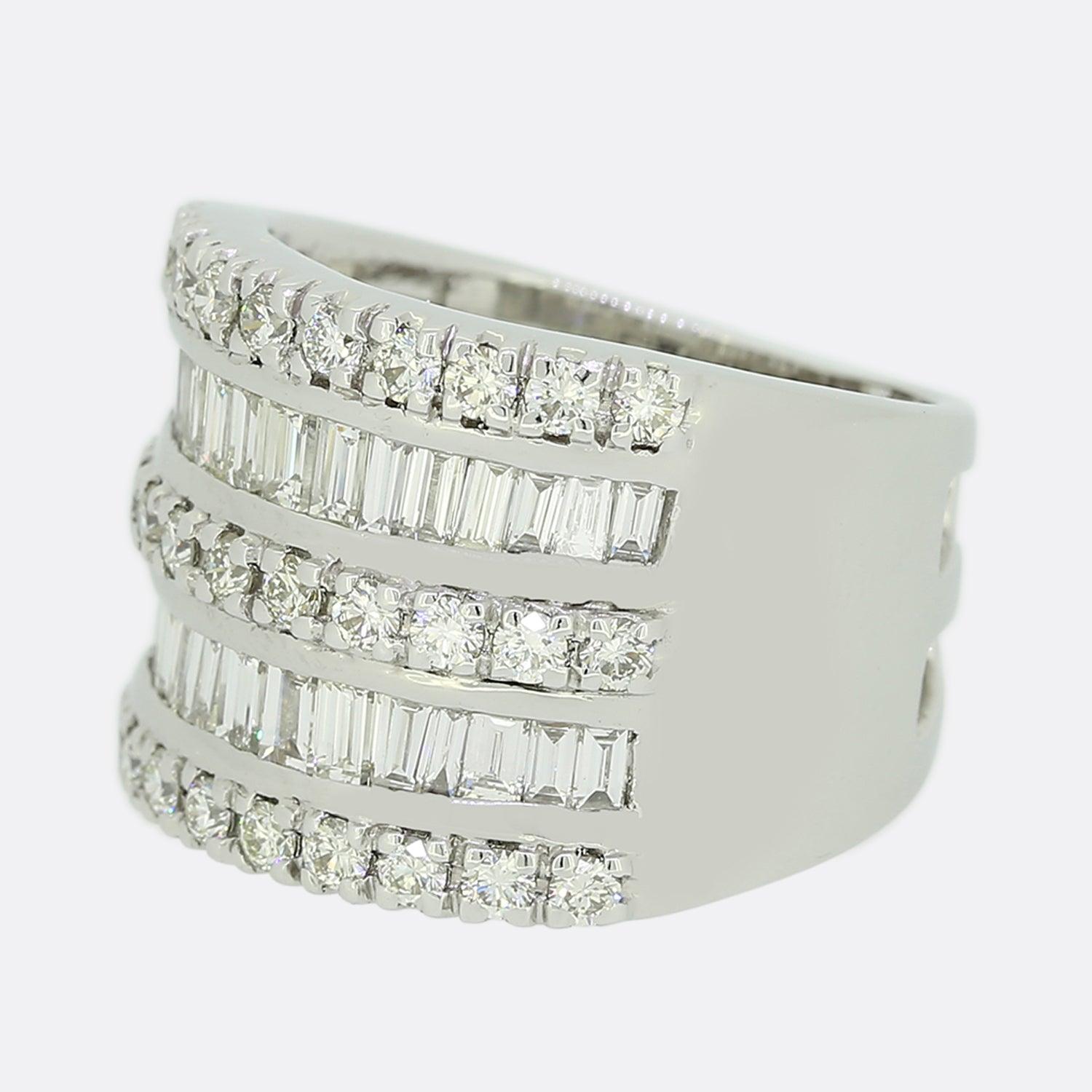 Here we have a large 14ct white gold diamond ring. The ring is split across 5 rows with alternating layers of round brilliant and baguette cut diamonds; all of which are set in single line formations. The piece is finished with wide plain polished