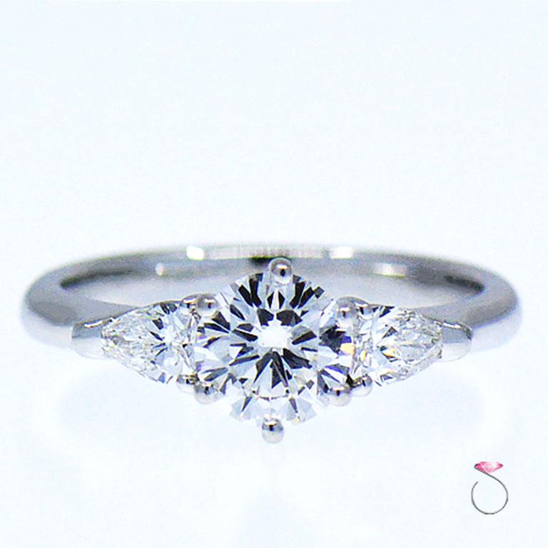 Stunning Platinum 3 stone engagement ring with 0.86 carat round brilliant diamond center and two pear shape side diamonds. The center diamond color grade is E, and clarity is VS1. The diamond is set in a six prong head for ultimate security. The two