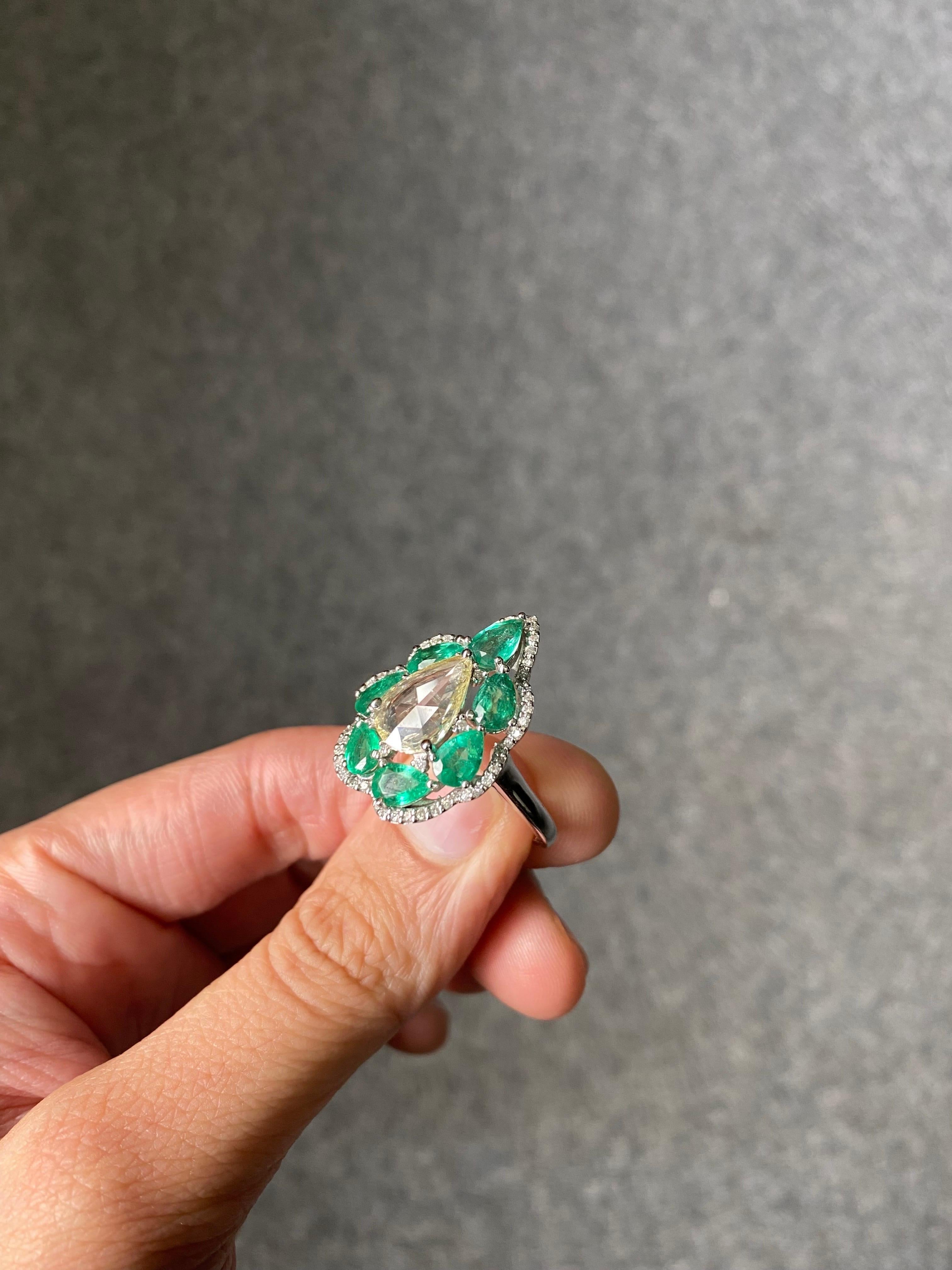 A stunning, art-deco looking, pear shaped 0.86 carat eye clean Rose Cut Diamond centre stone, with 2.66 carat pear shaped Zambian Emerald with great luster and vivid green color. The gemstones are set in solid 18K White Gold. The ring is currently