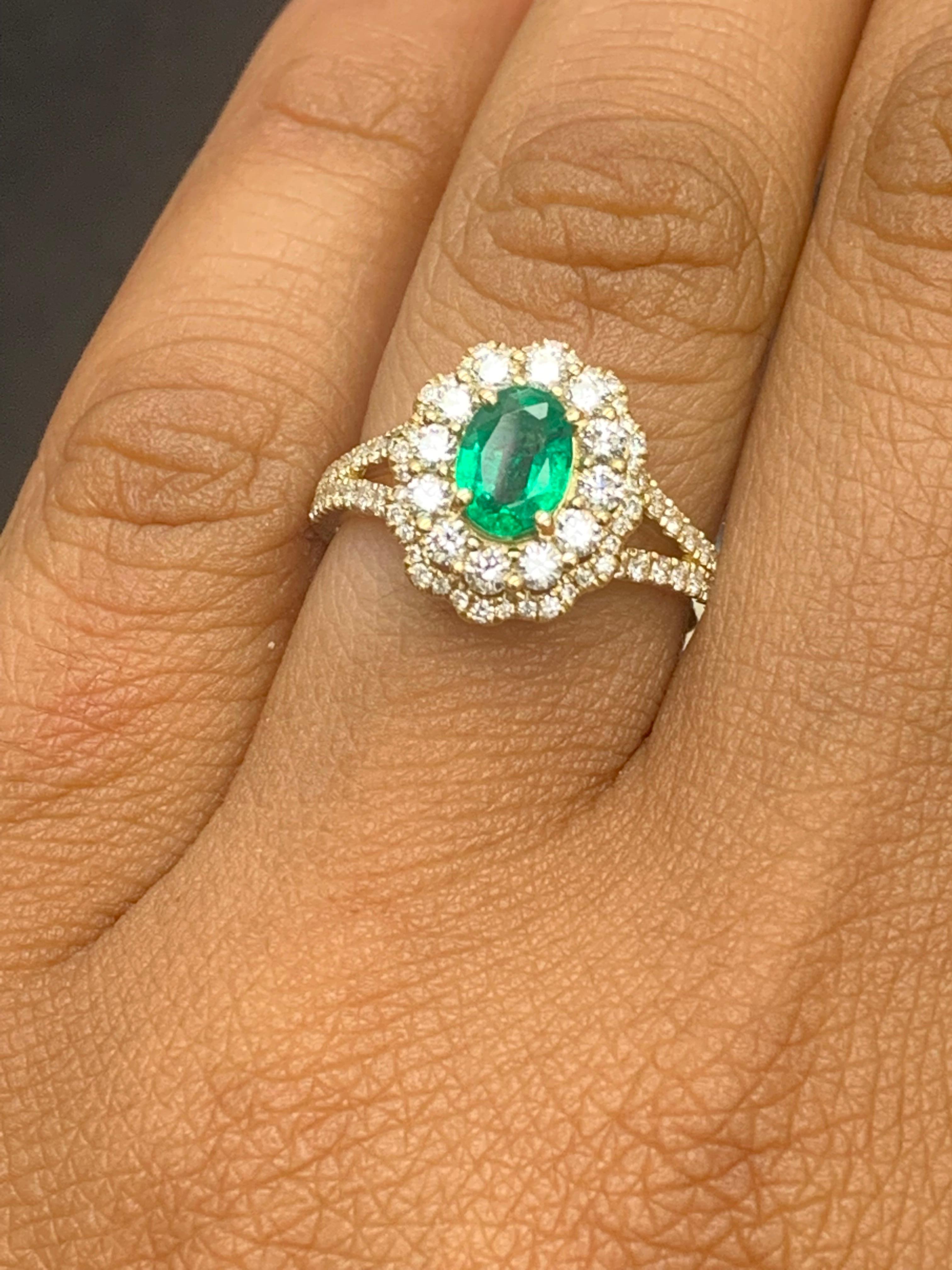 Dieser wunderschöne Ring zeigt ein hübsches florales Design mit einem atemberaubenden grünen Smaragd von 0,88 Karat im Ovalschliff in der Mitte. Er wird von zwei Reihen funkelnder Diamanten im Brillantschliff akzentuiert, die zusammen 0,79 Karat
