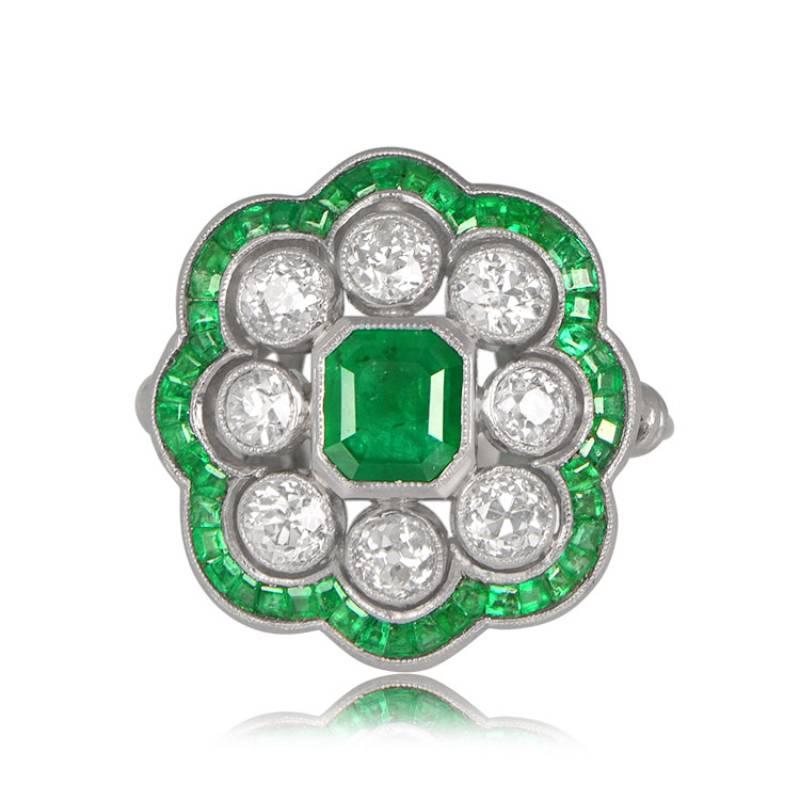 This enchanting engagement ring features a lively natural emerald, approximately 0.89 carats, at its center. Surrounding the emerald is a cluster of diamonds and a row of calibre-cut emeralds, totaling approximately 1.00 carat in diamond weight.