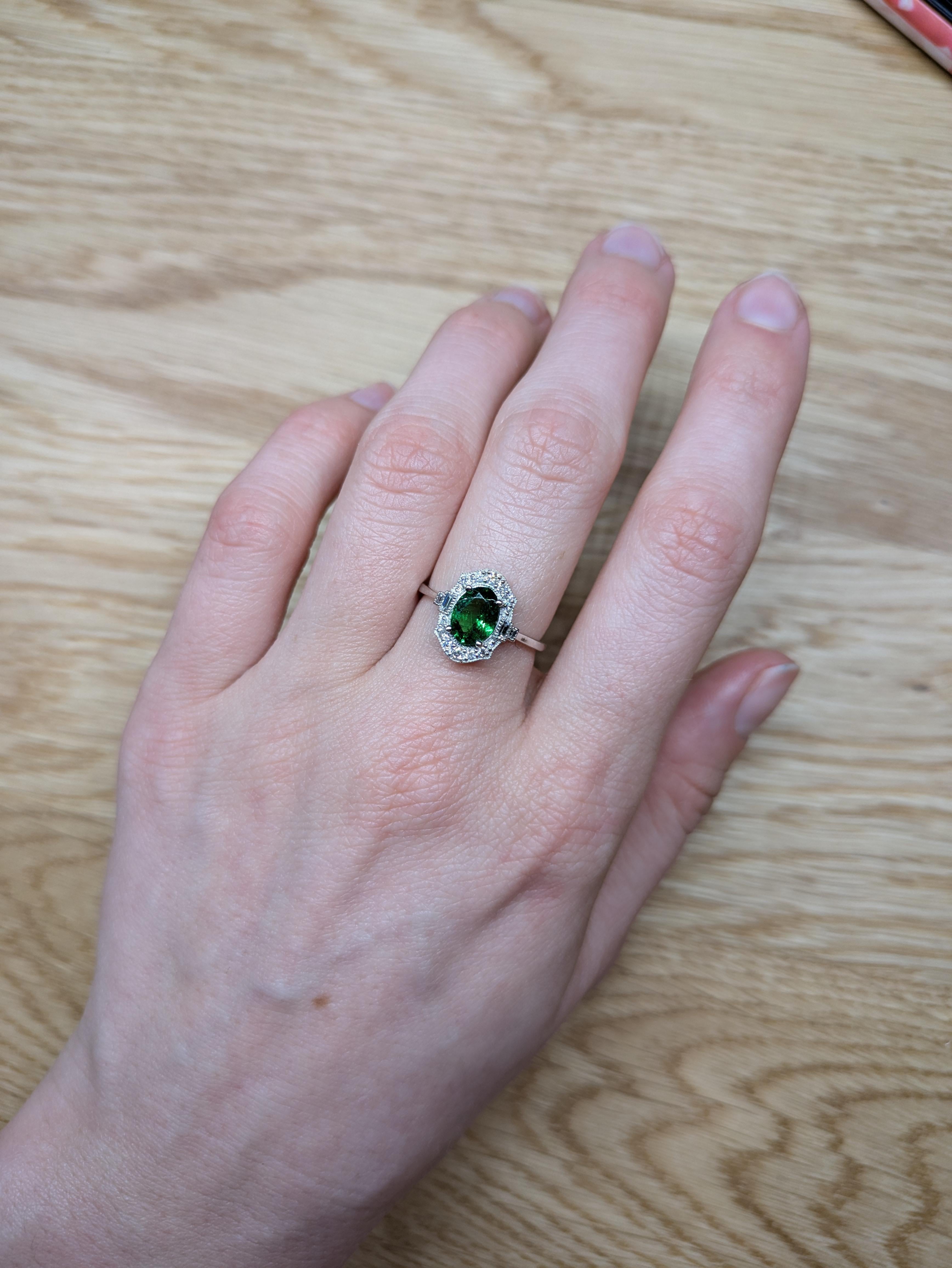 Este anillo de oro blanco de 14 quilates, de inspiración vintage, presenta una llamativa tsavorita ovalada de 0,94 quilates y 8x6 mm de tamaño, acentuada con brillantes diamantes extraídos de la tierra. Una pieza atemporal que captura el encanto del