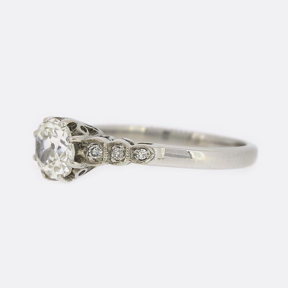 Dies ist ein Solitär-Verlobungsring aus 18 Karat Weißgold. Der Ring enthält einen 0,90 Karat schweren Diamanten im Kissenschliff, der in eine Fassung mit acht Klauen und diamantbesetzten Schultern eingefasst ist.

Zustand: Gebraucht (Sehr