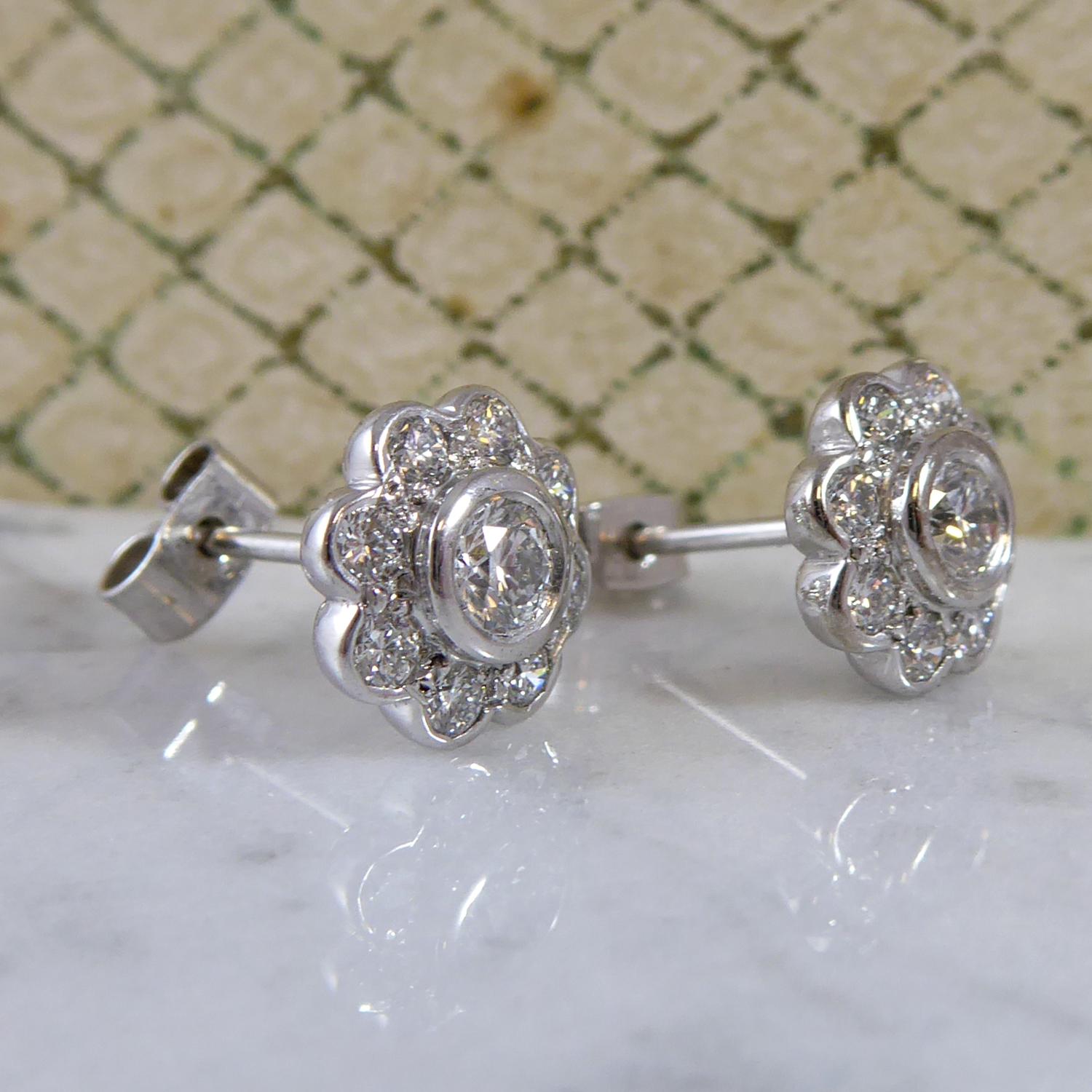A pair of stunning vintage diamond stud earrings, probably circa 1950's/1960's.  Set to the centre with a round brilliant cut diamond, 3.8mm diameter, in white rub over mount to a surround of eight round brilliant cut diamonds, each measuring