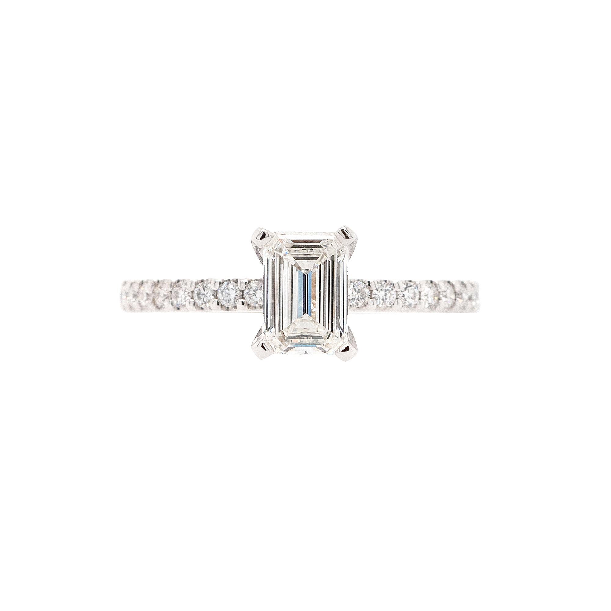 This Diamond Engagement Ring features a natural 0.90ct Emerald Cut Diamond with I color and VVS2 clarity. Made by Gabriel & Co., the ring is crafted from 14k white gold and showcases 0.36ctw of Round cut Diamonds with G/H color and VS clarity. It