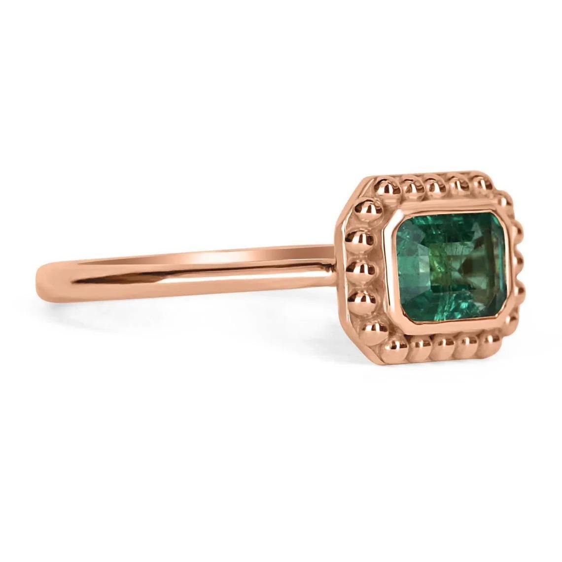 Displayed is a stunning East to West emerald-emerald cut solitaire ring in 14K rose gold. This gorgeous solitaire ring carries a 0.90-carat emerald in a bezel setting. Fully faceted, this gemstone showcases excellent shine and beautiful, rich green