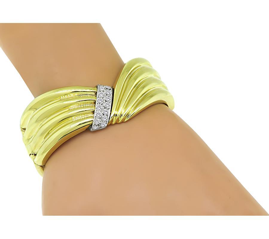 This is an elegant 14k yellow and white gold bangle. The bangle is set with sparkling round cut diamonds that weigh approximately 0.90ct. The color of these diamonds is H with VS clarity. The bangle measures 25mm in at the widest base and will fit a