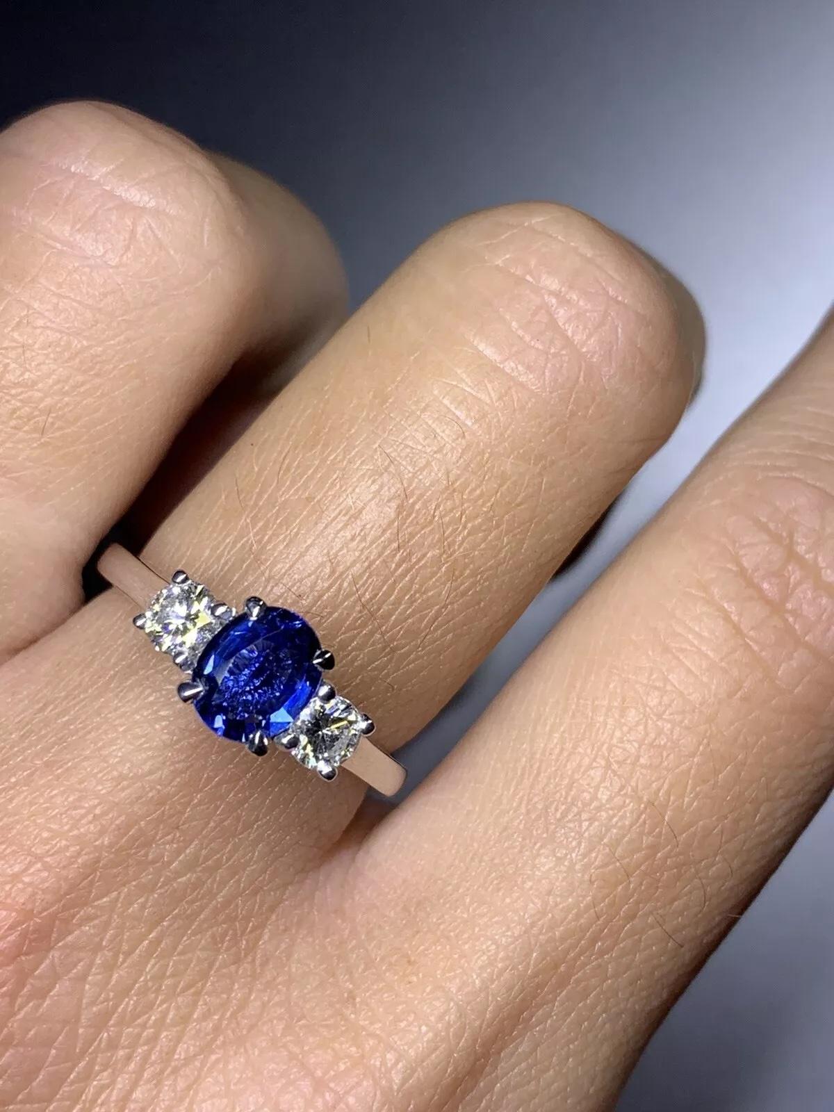 In diesem atemberaubenden Verlobungsring steht ein natürlicher, ovaler Saphir im Mittelpunkt, umgeben von zwei Diamanten im Brillantschliff auf beiden Seiten. Der Saphir hat eine schöne blaue Farbe und ist nicht veredelt, während die Diamanten einen