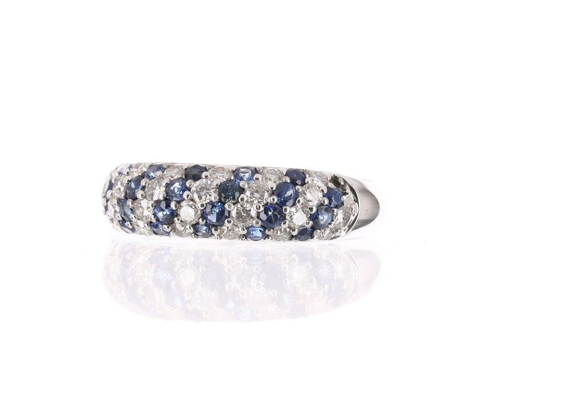 Displayed is a stunning sapphire and diamond pave band that is modern and chic. Created in solid 14 karat gold, this ring showcases numerous precious stones alternating from sapphire to diamond. The sapphires have lovely saturation and the color