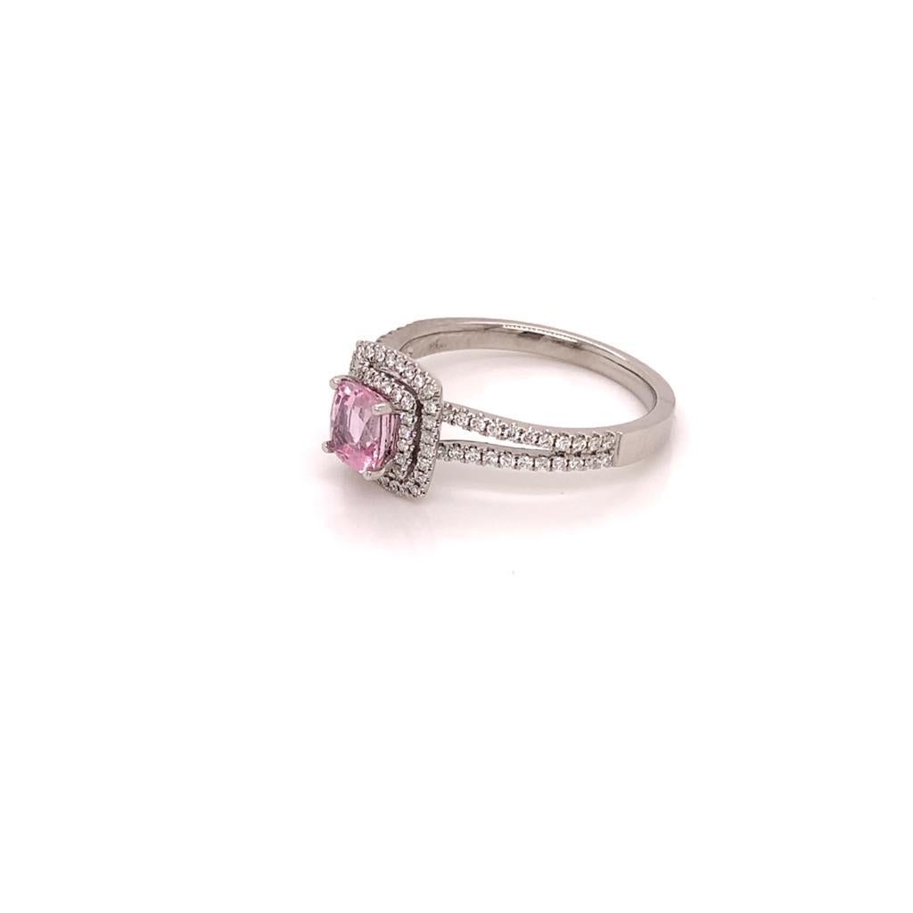 At the centre of this Stunning Ring is a Pristine Cushion Cut Padparadscha Sapphire, weighing approximately 0.91 Carats and surrounded by two rows of Round Brilliant Diamonds weighing approximately 0.48 Carats. The Diamonds extend to the 18K White