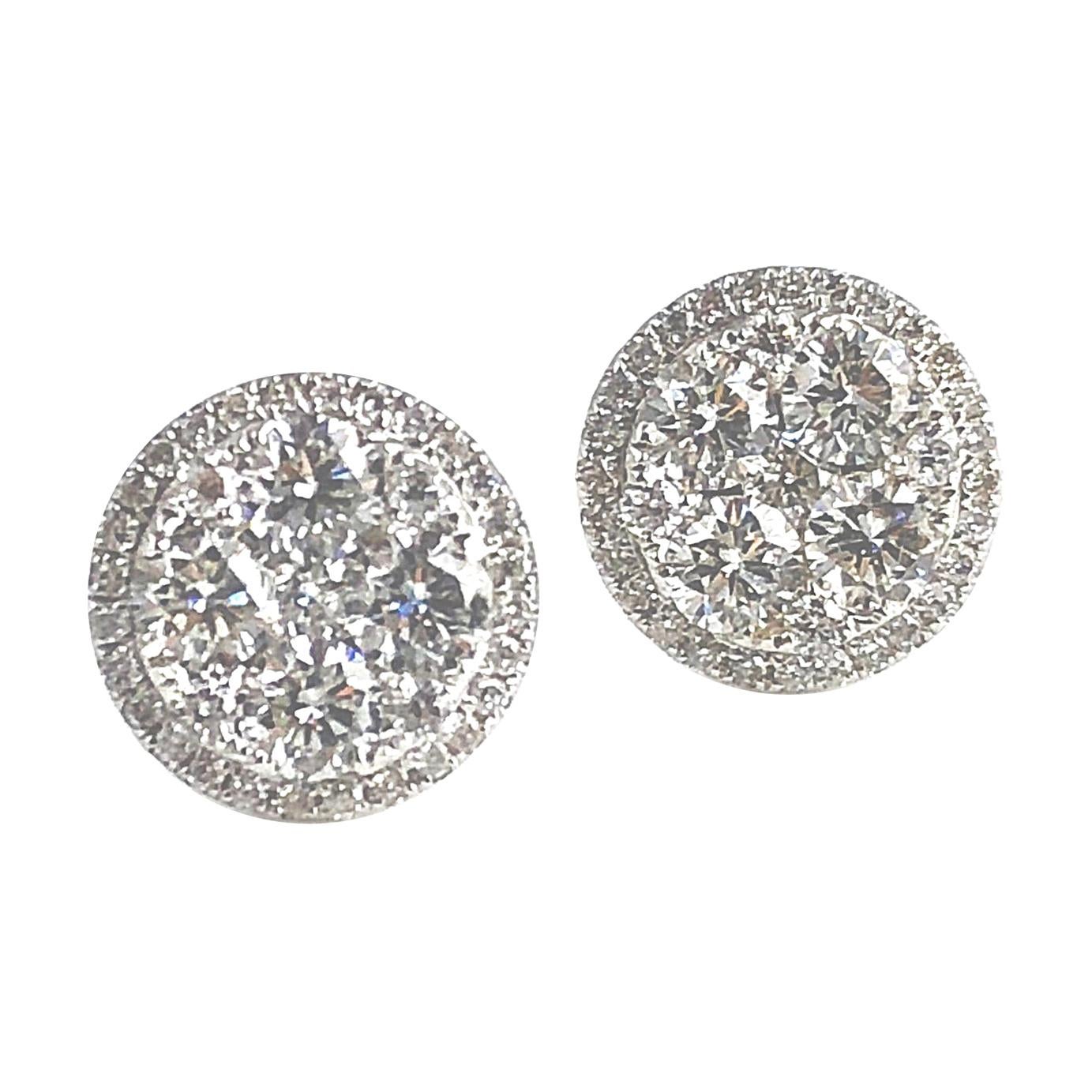 Elevate your style with these stud earrings showcasing a brilliant central cluster of round natural diamonds, elegantly encircled by an additional shimmering halo of round natural diamonds. Crafted in lustrous 14k White Gold, the total diamond