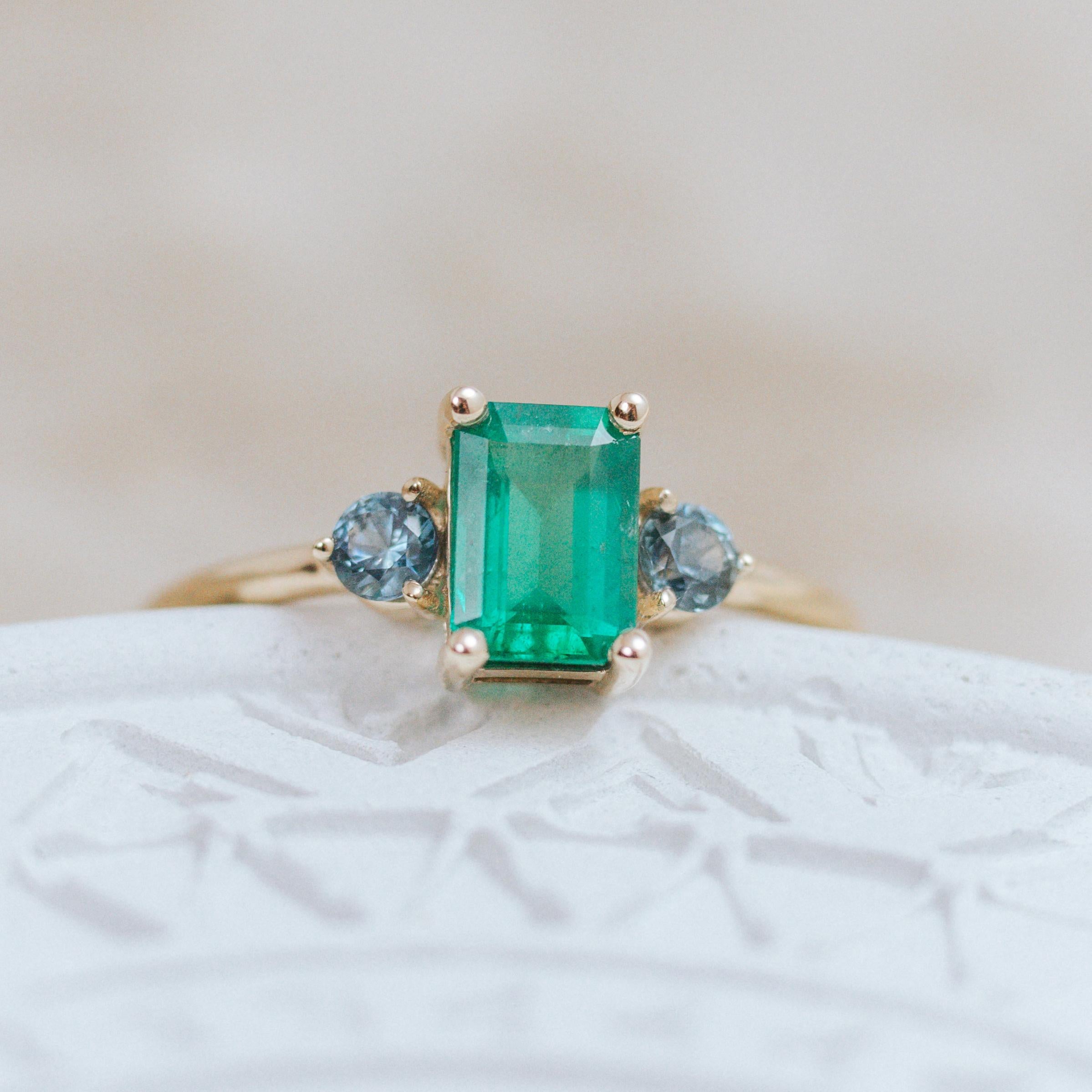 Ring in 14k yellow gold, set with emerald from Brazil and Montana sapphires.
This ring takes us to the shores of the blue ocean and the green jungles of Maui.
The ring is made in 14k yellow gold, set with a natural emerald 0.91ct, emerald-cut,