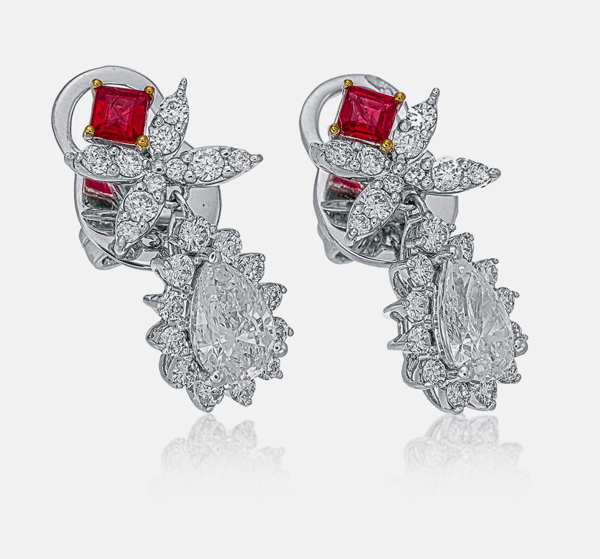 These earrings feature 0.92 carats of pear-cut diamonds. The center stones are beautifully complemented by 0.60 carats of sparkling round-cut diamonds and 0.24 carats of vibrant square-cut rubies, adding a touch of color. Crafted in 18-karat white